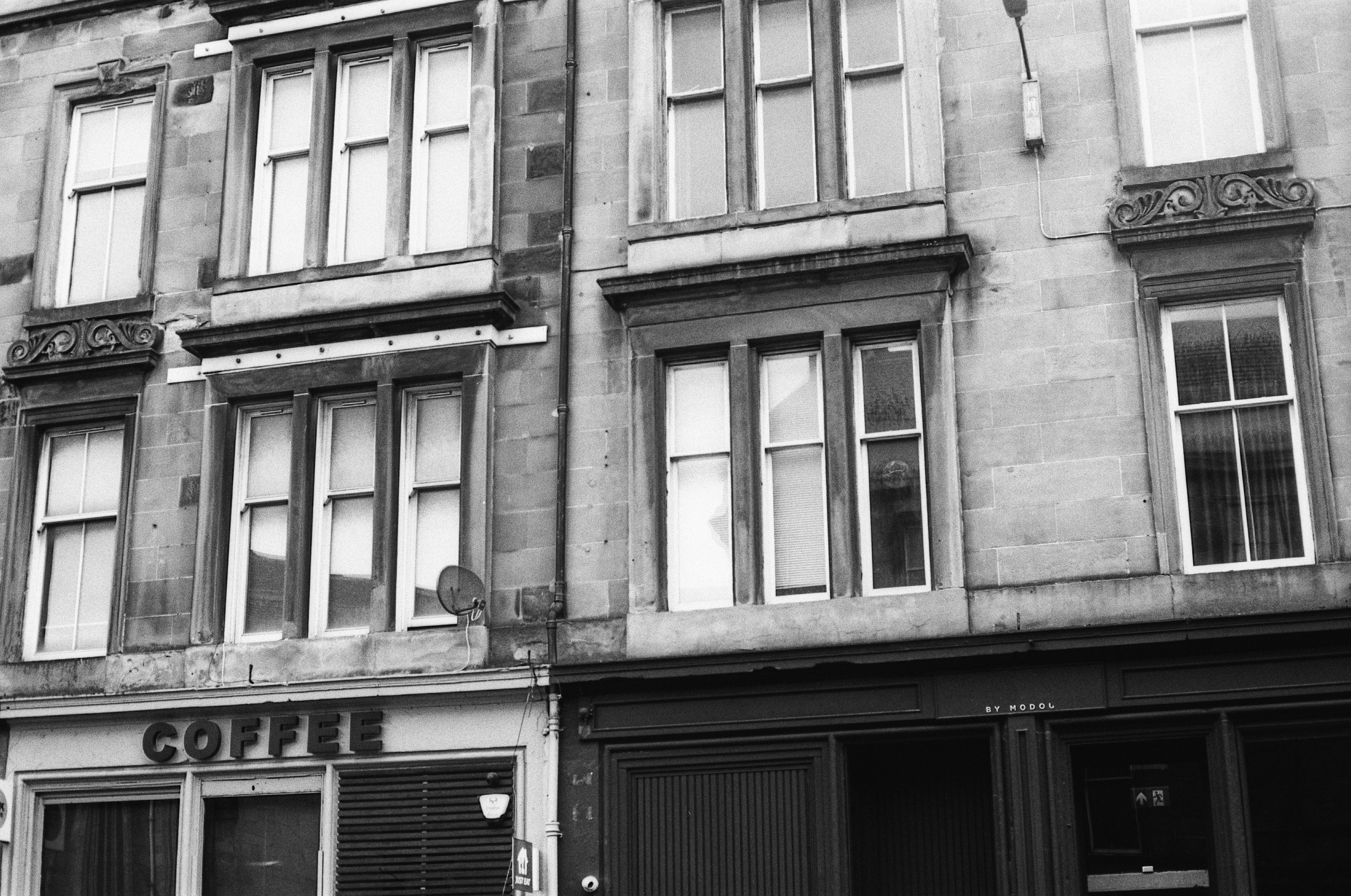 A stone building facade with sash windows and a coffee shop storefront