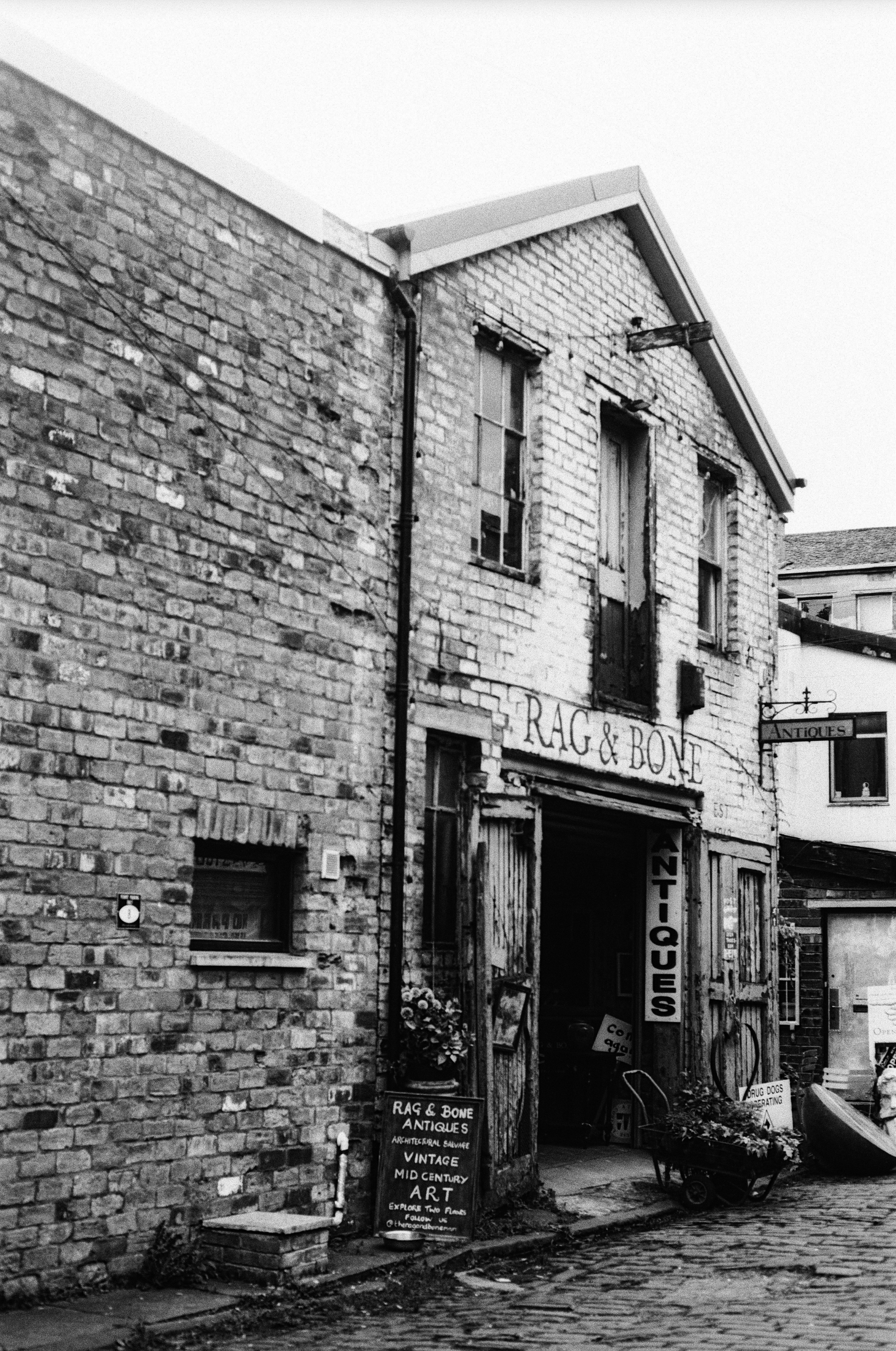 A brick building with a sign reading "RAG & BONE" above an antiques shop entrance