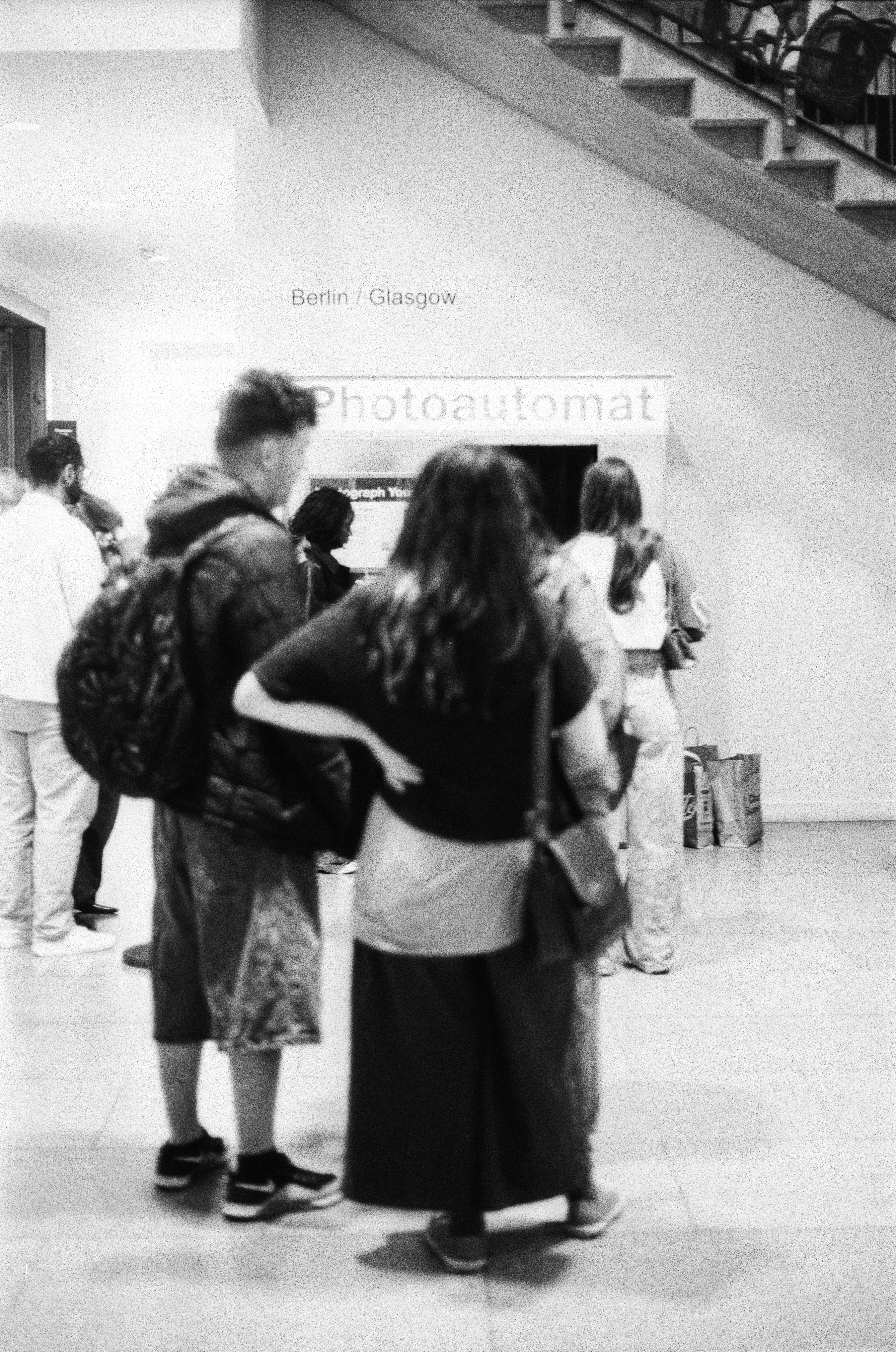 A group of people waiting in line for a Photoautomat booth indoors