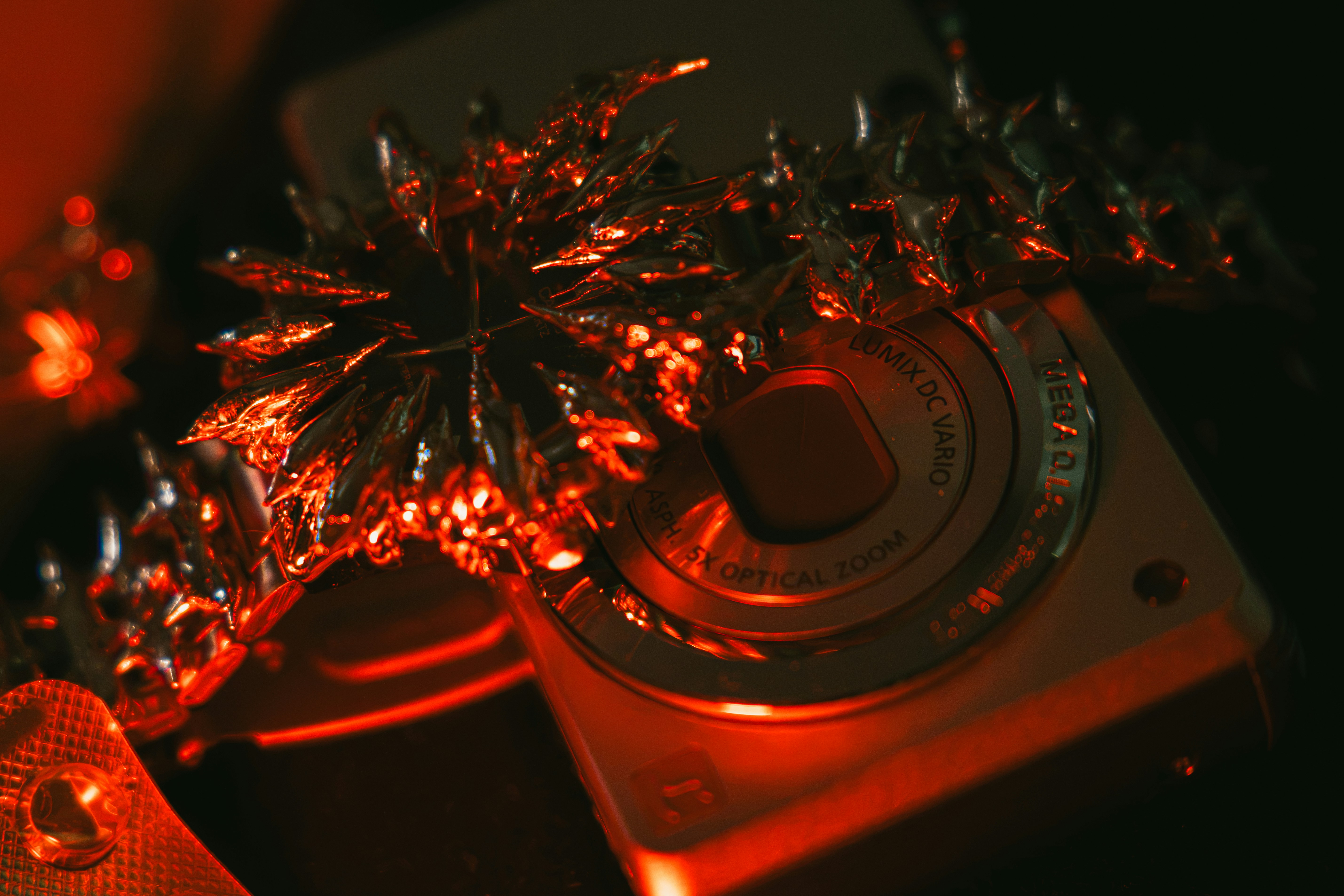 A metallic spiked bracelet resting on a compact digital camera under red light