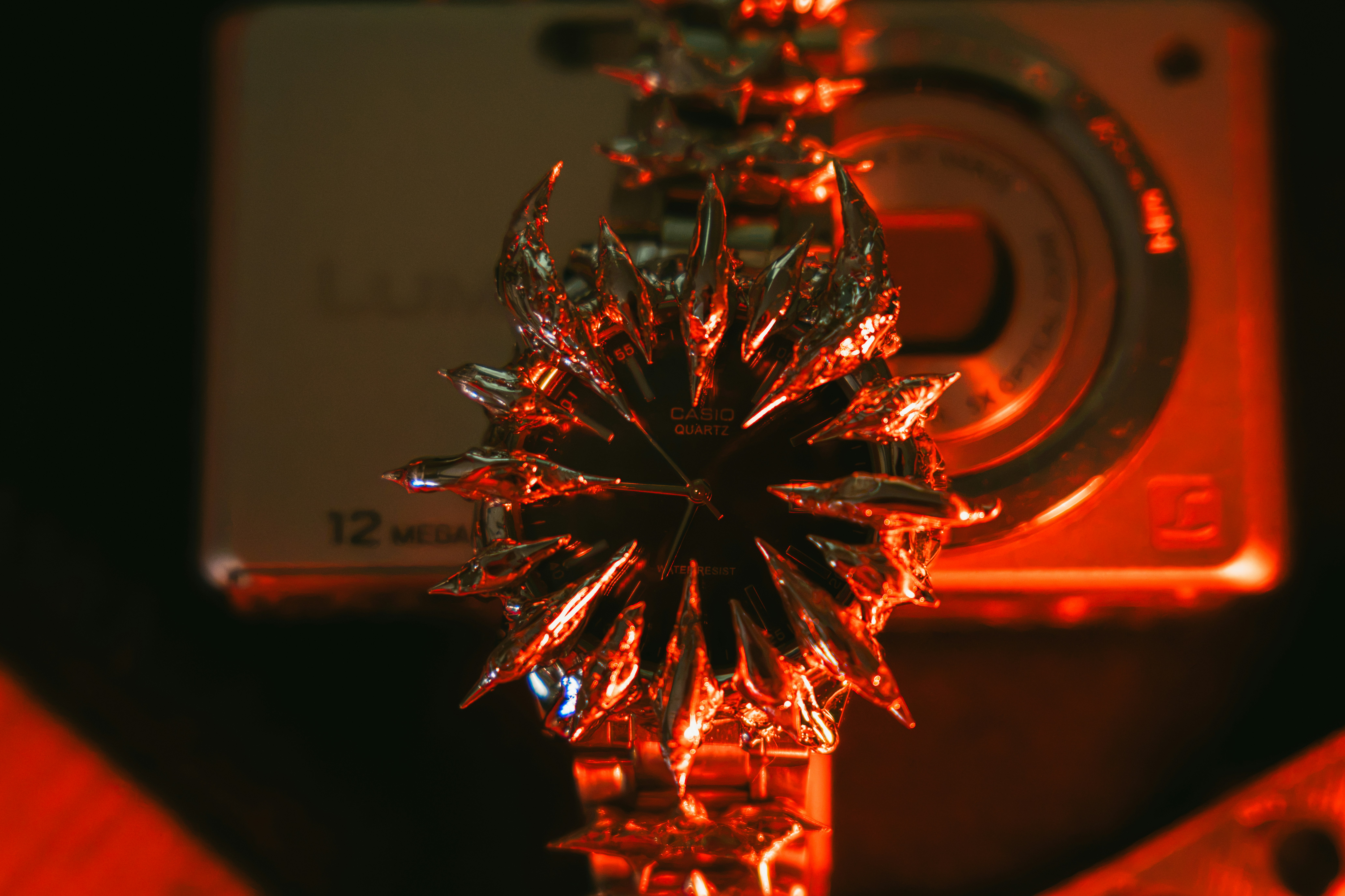 A Casio watch with a spiked metallic bezel under red light