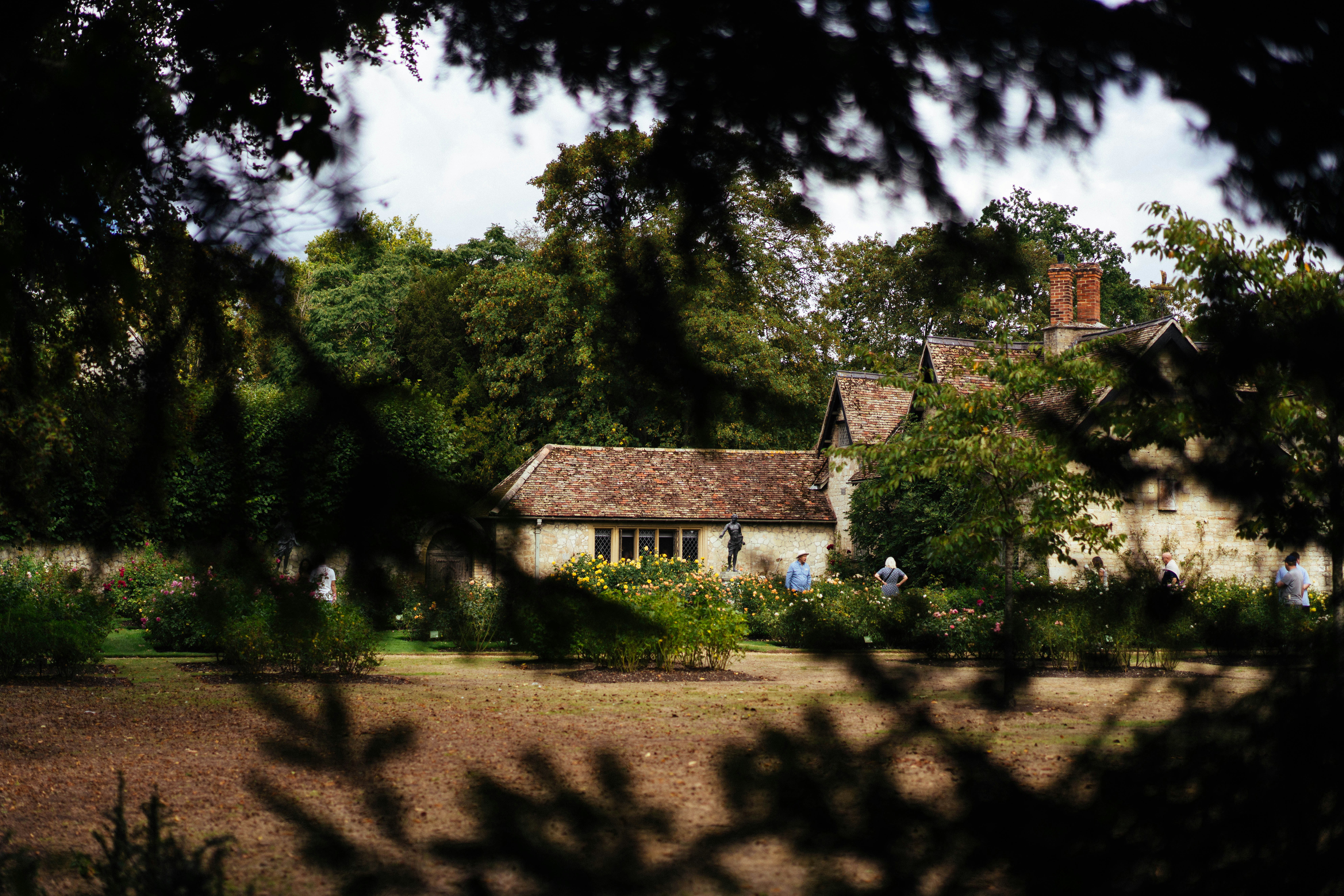 People walking through a rose garden in front of a stone cottage