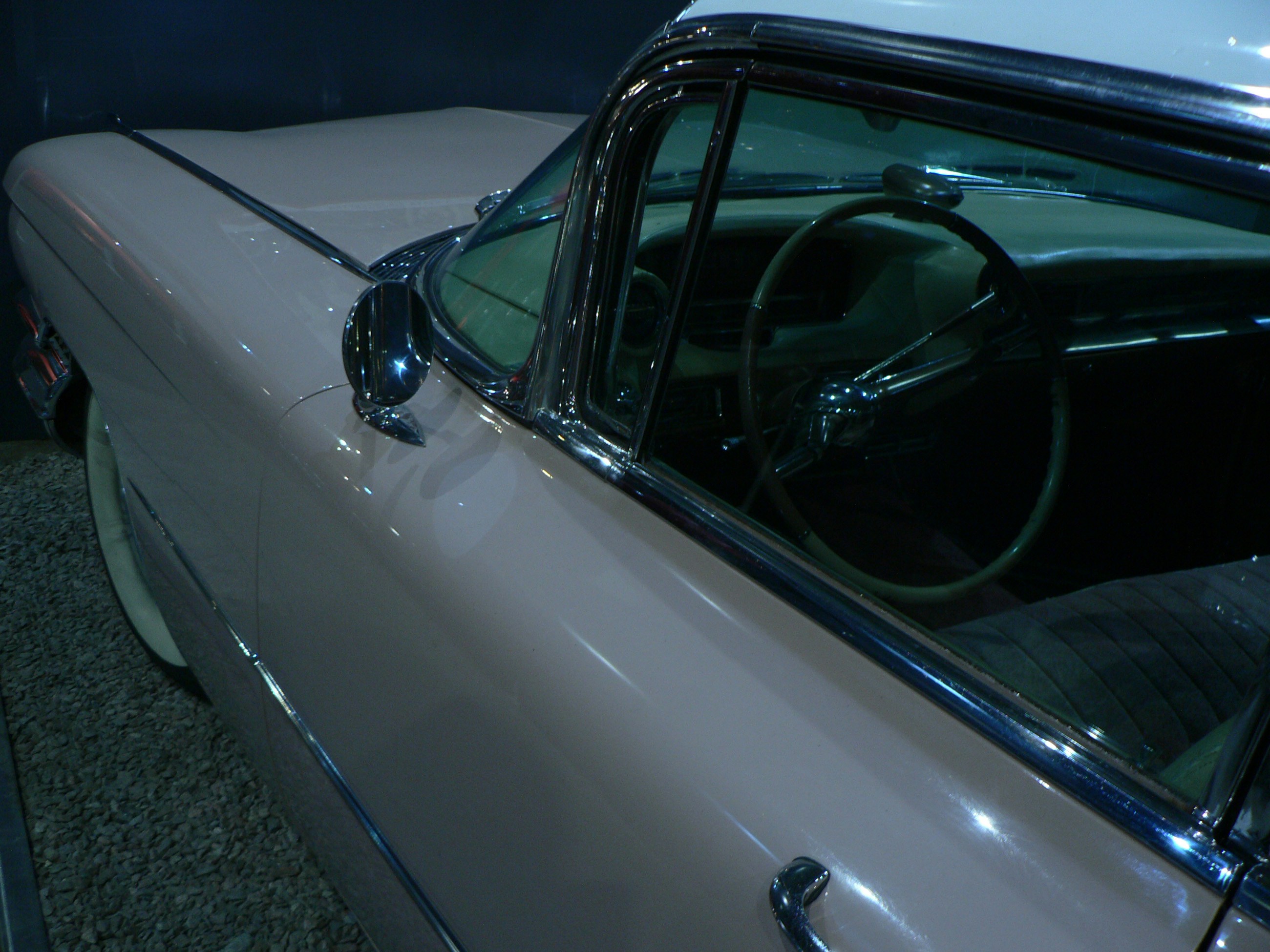 A vintage pink car with chrome trim and a steering wheel in view