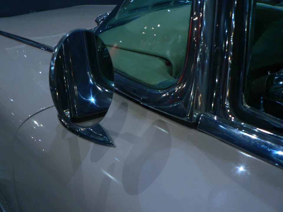 Chrome side mirror and polished trim on a vintage Cadillac Sedan DeVille