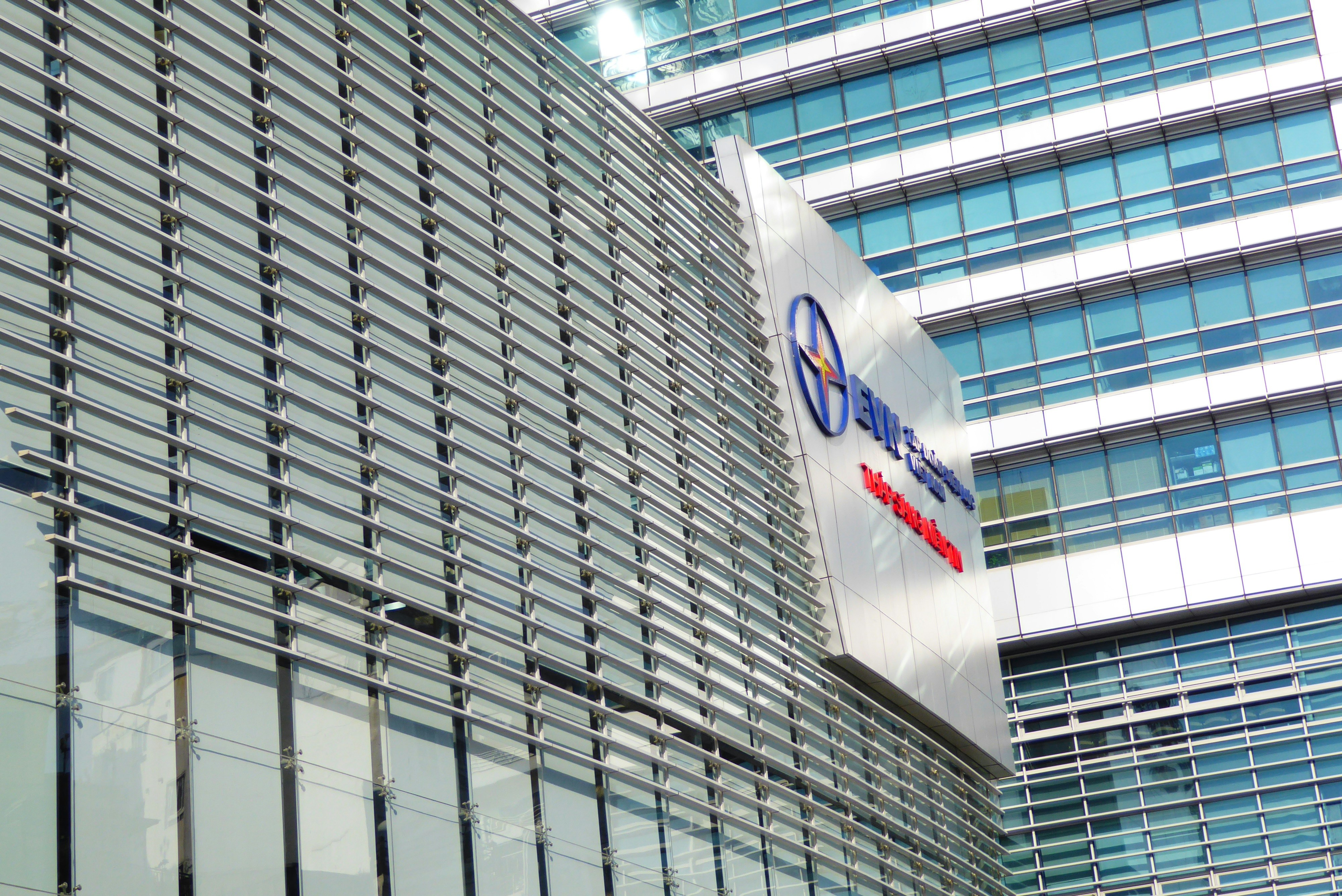 A modern glass office building with horizontal metal louvers and a corporate logo