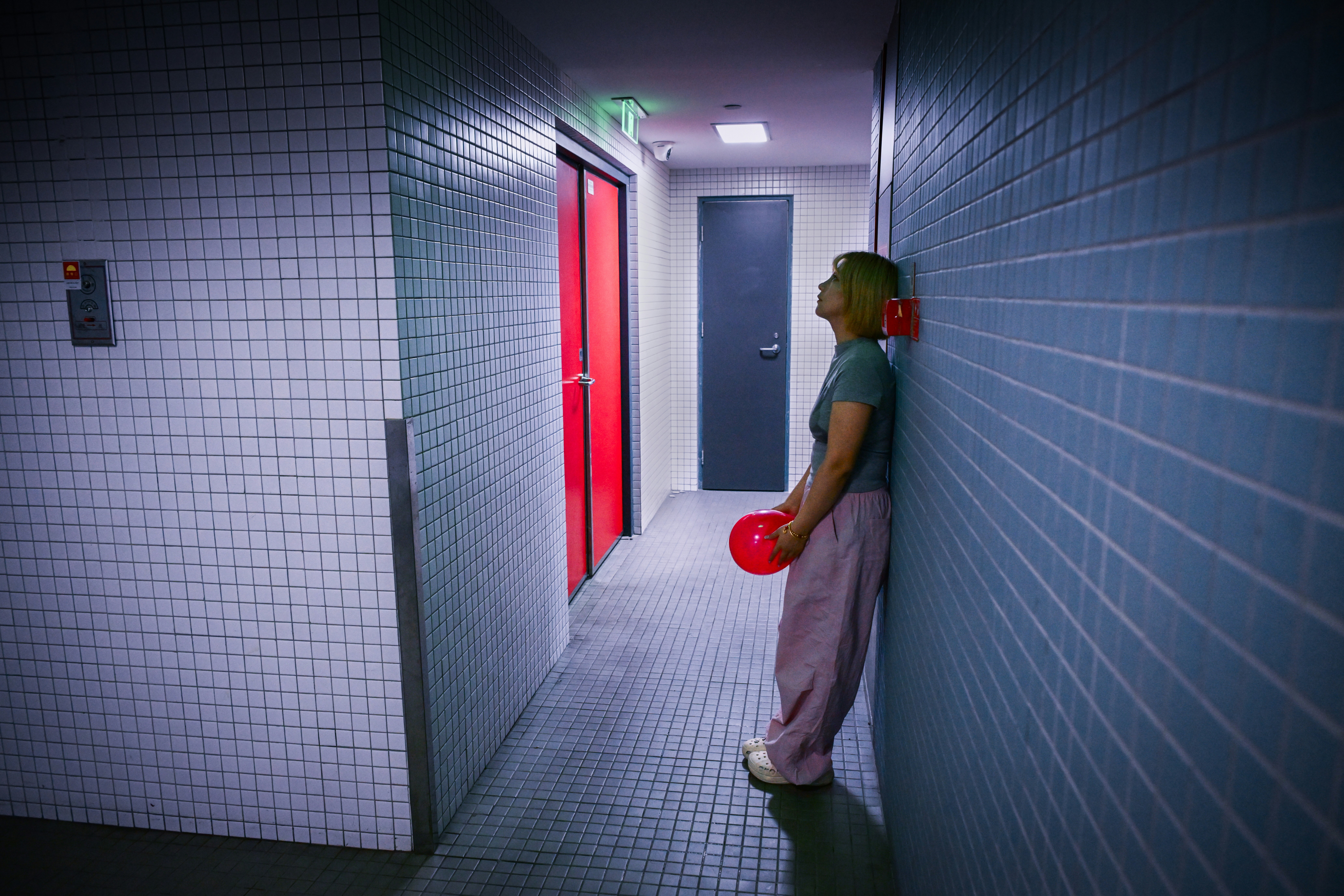 A woman holding a red balloon in a hallway