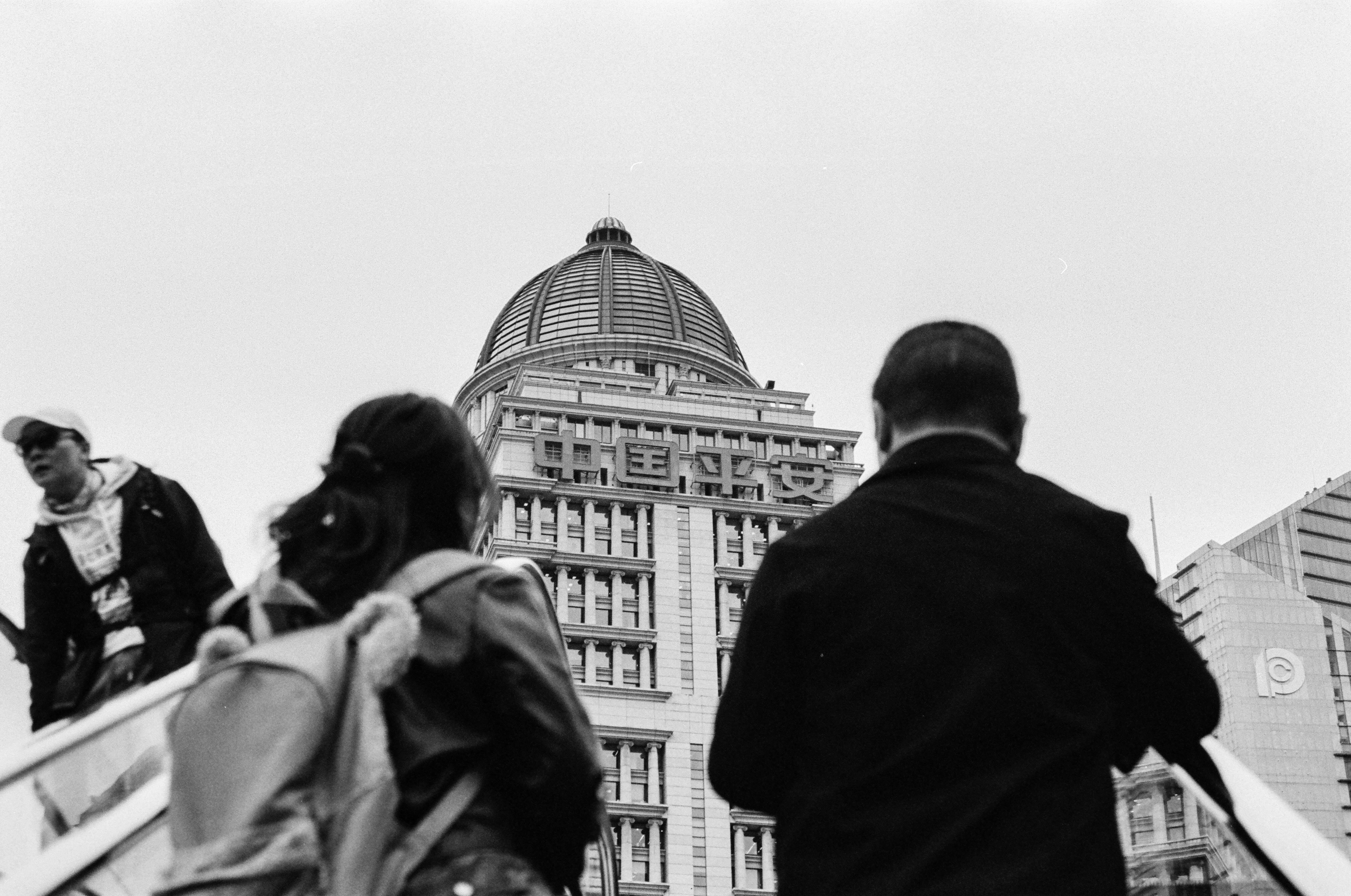 People on an escalator in front of a building with a domed roof