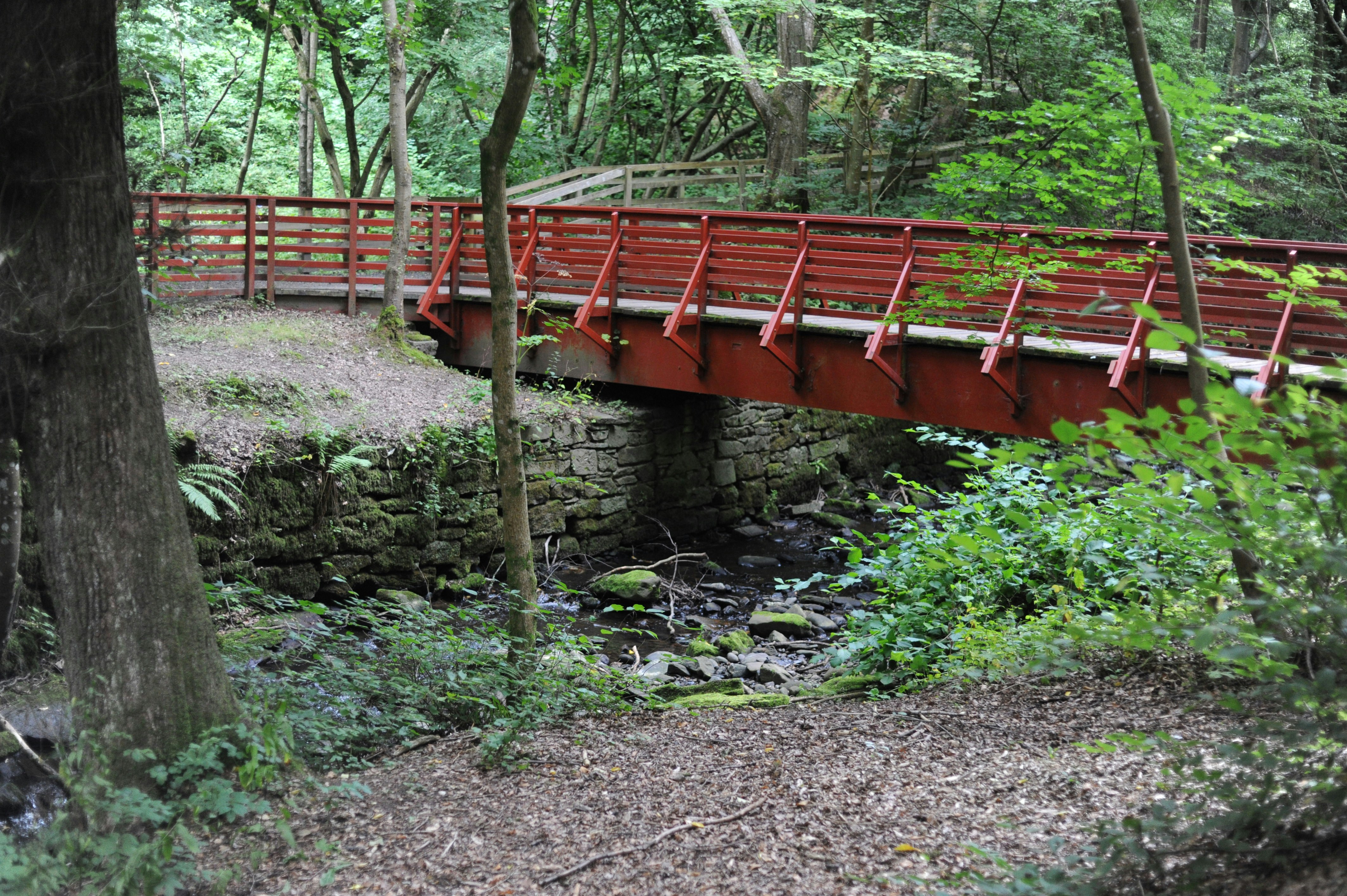 Red wooden footbridge over a small creek