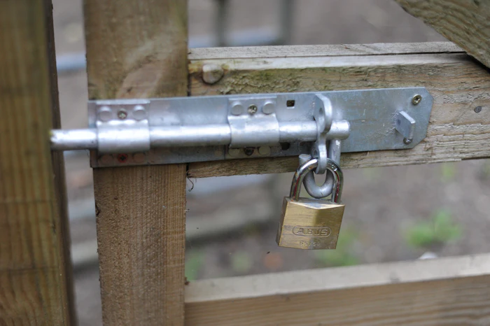 Padlocked slide-bolt latch on a wooden gate