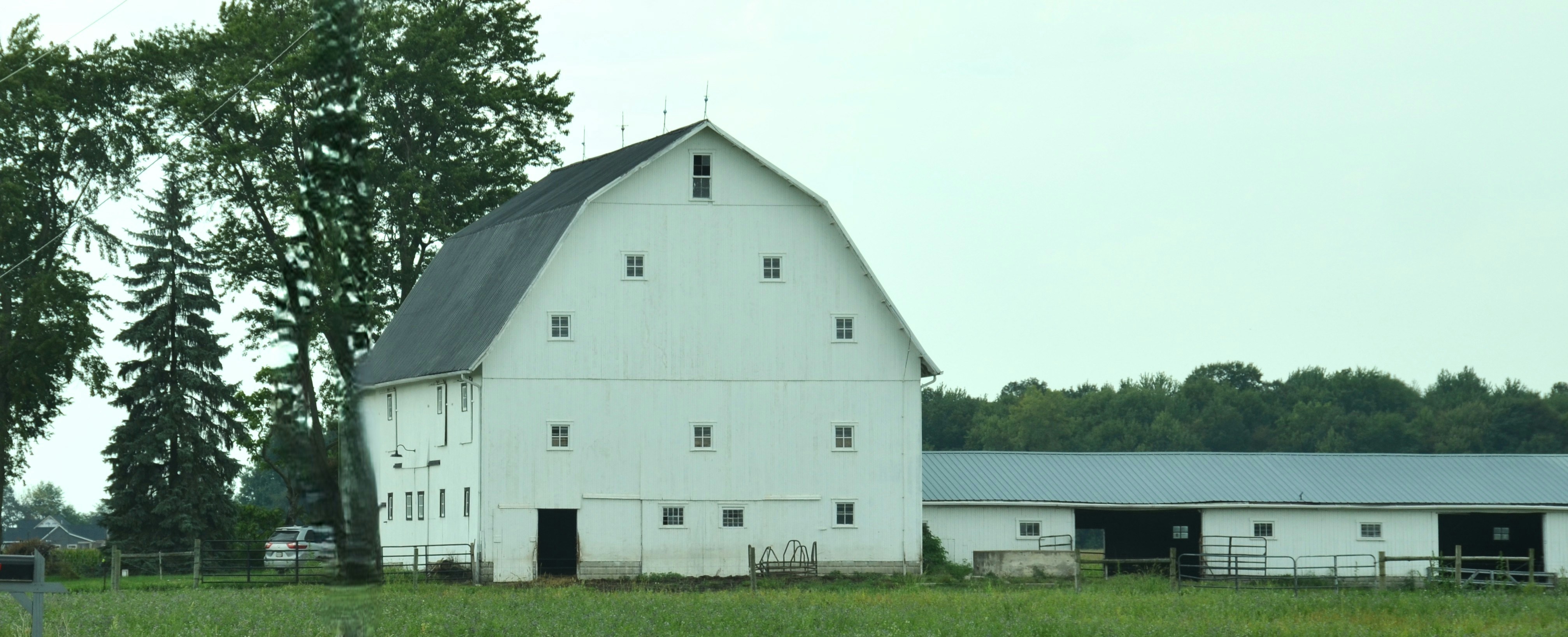 Eine große weiße Scheune mit Gambrel-Dach auf einem grünen Feld