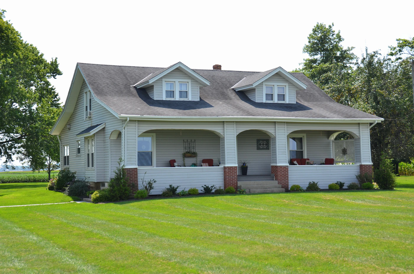 White farmhouse with a covered porch and a green lawn
