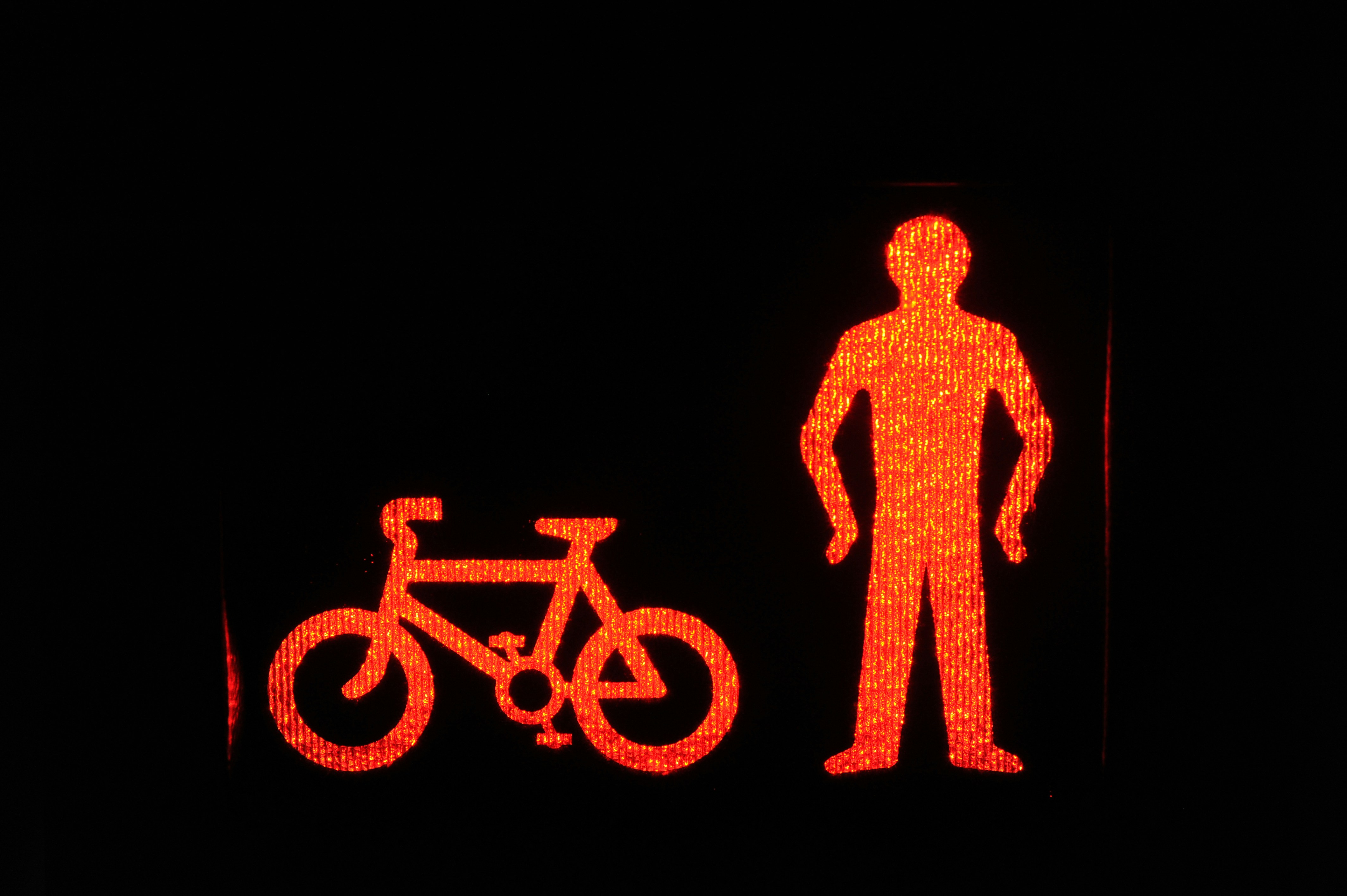 A glowing red pedestrian and bicycle signal against a black background