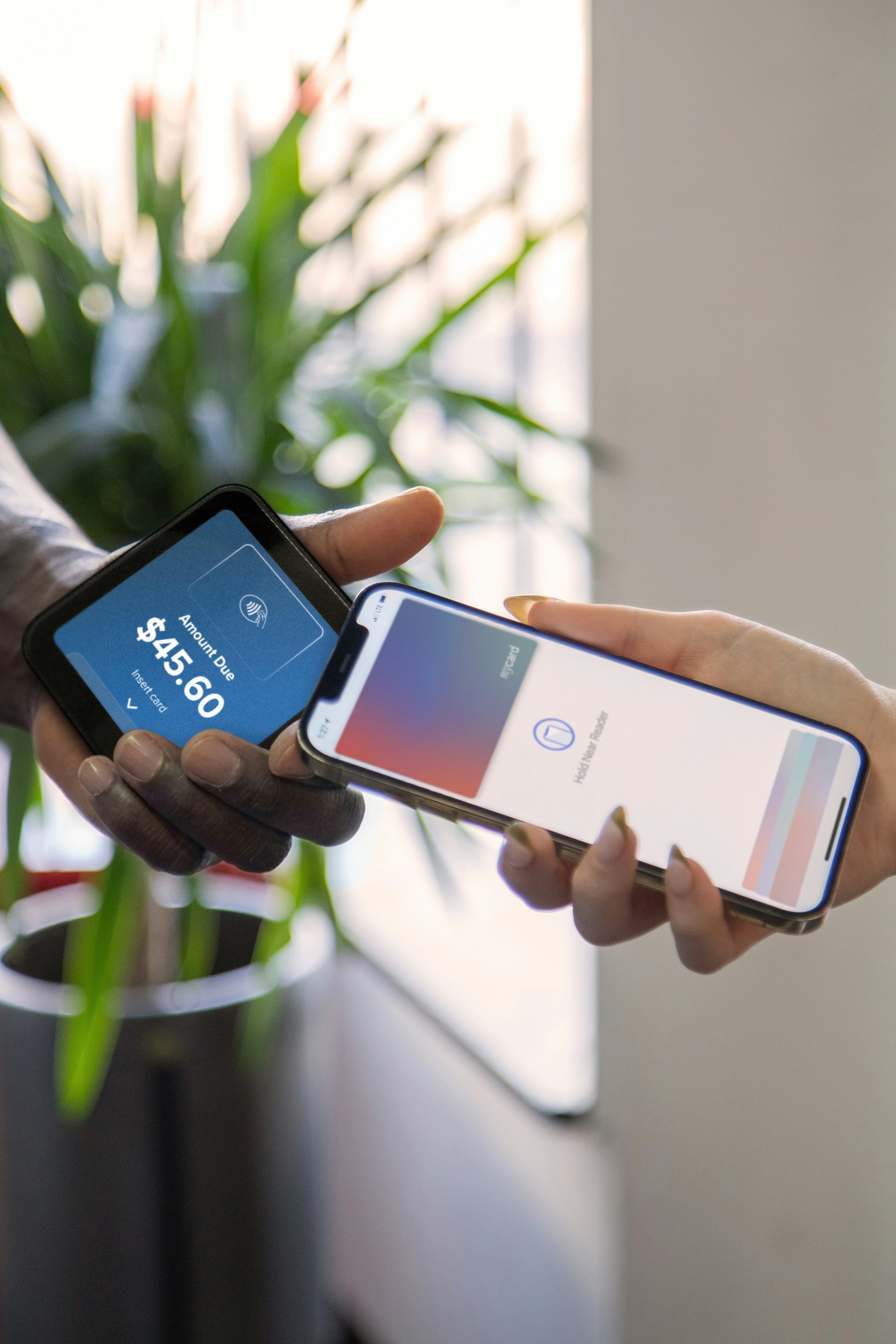 A person holding a smartphone near a payment terminal displaying an amount due