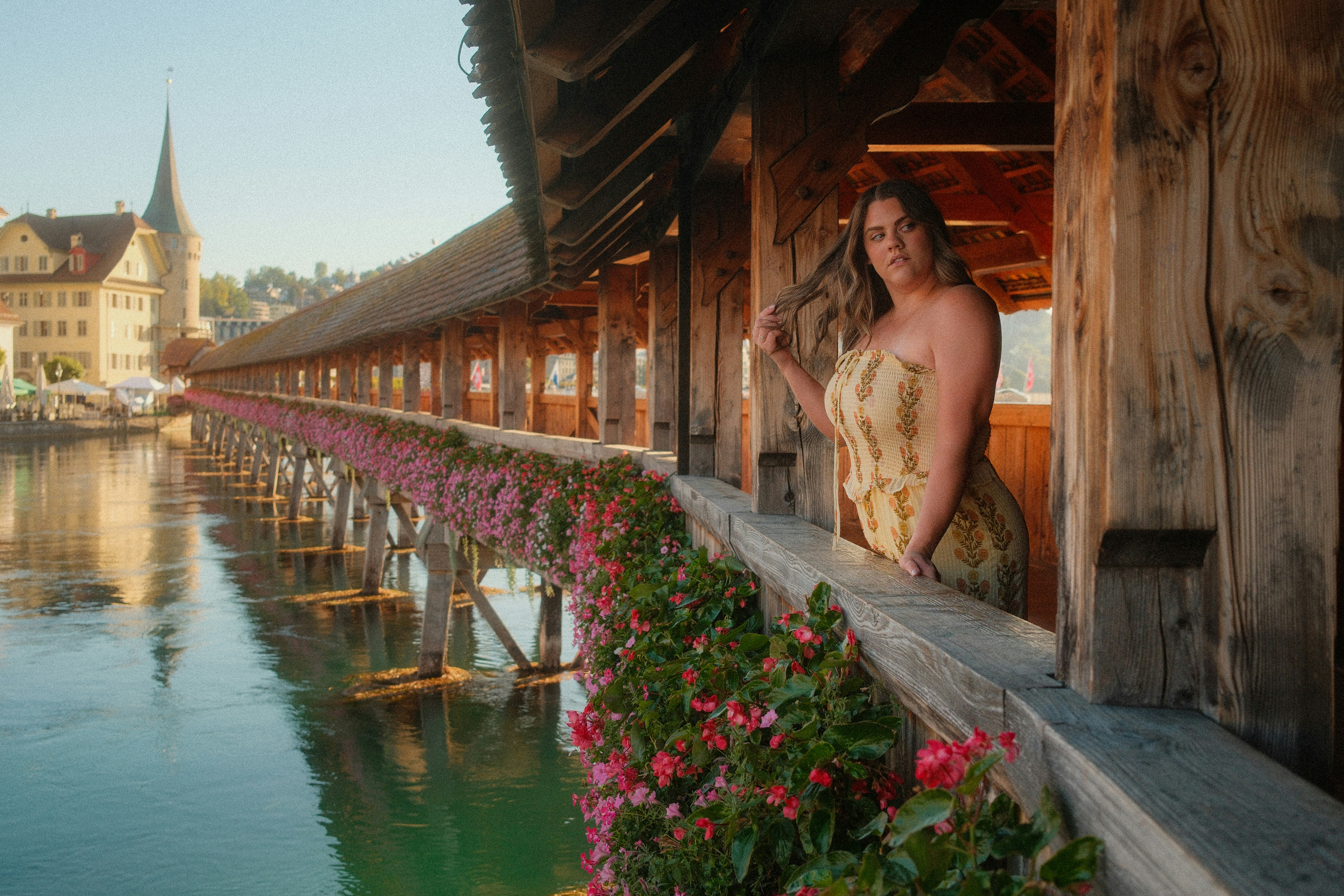 Une femme en robe jaune sur le pont de la chapelle tapissé de fleurs à Lucerne