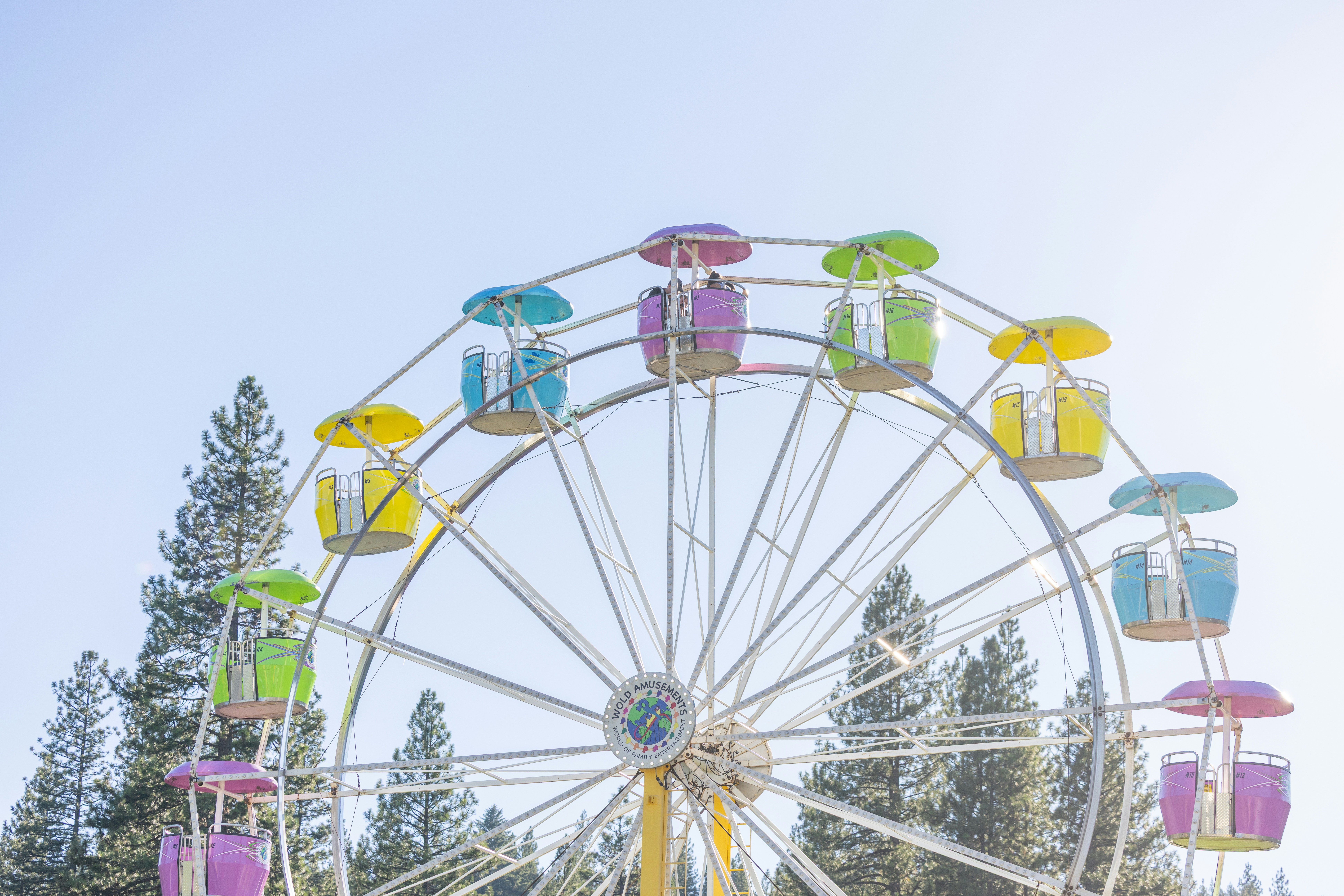 A colorful ferris wheel with passenger cars against a clear blue sky