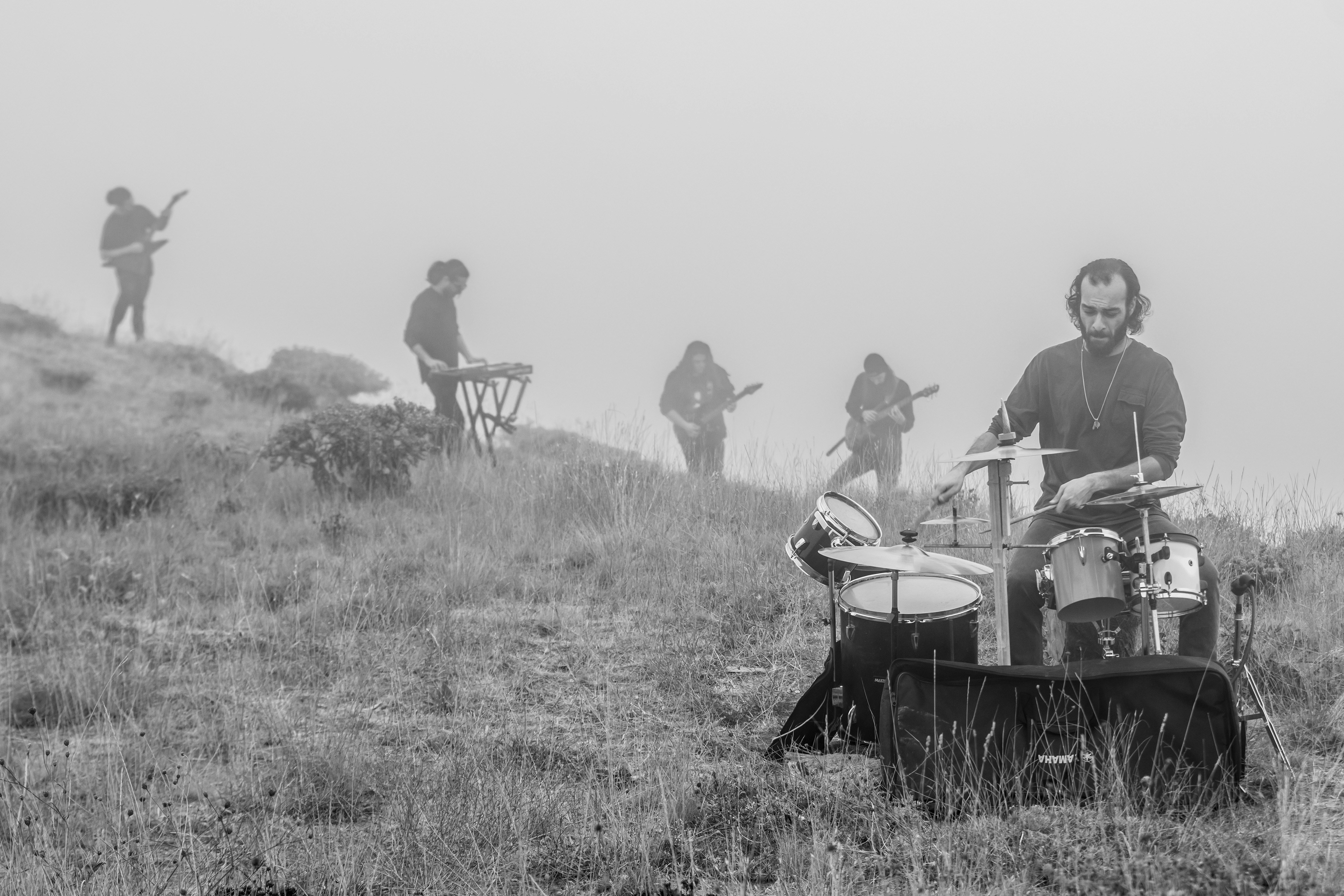 A band playing instruments on a grassy hillside in thick fog