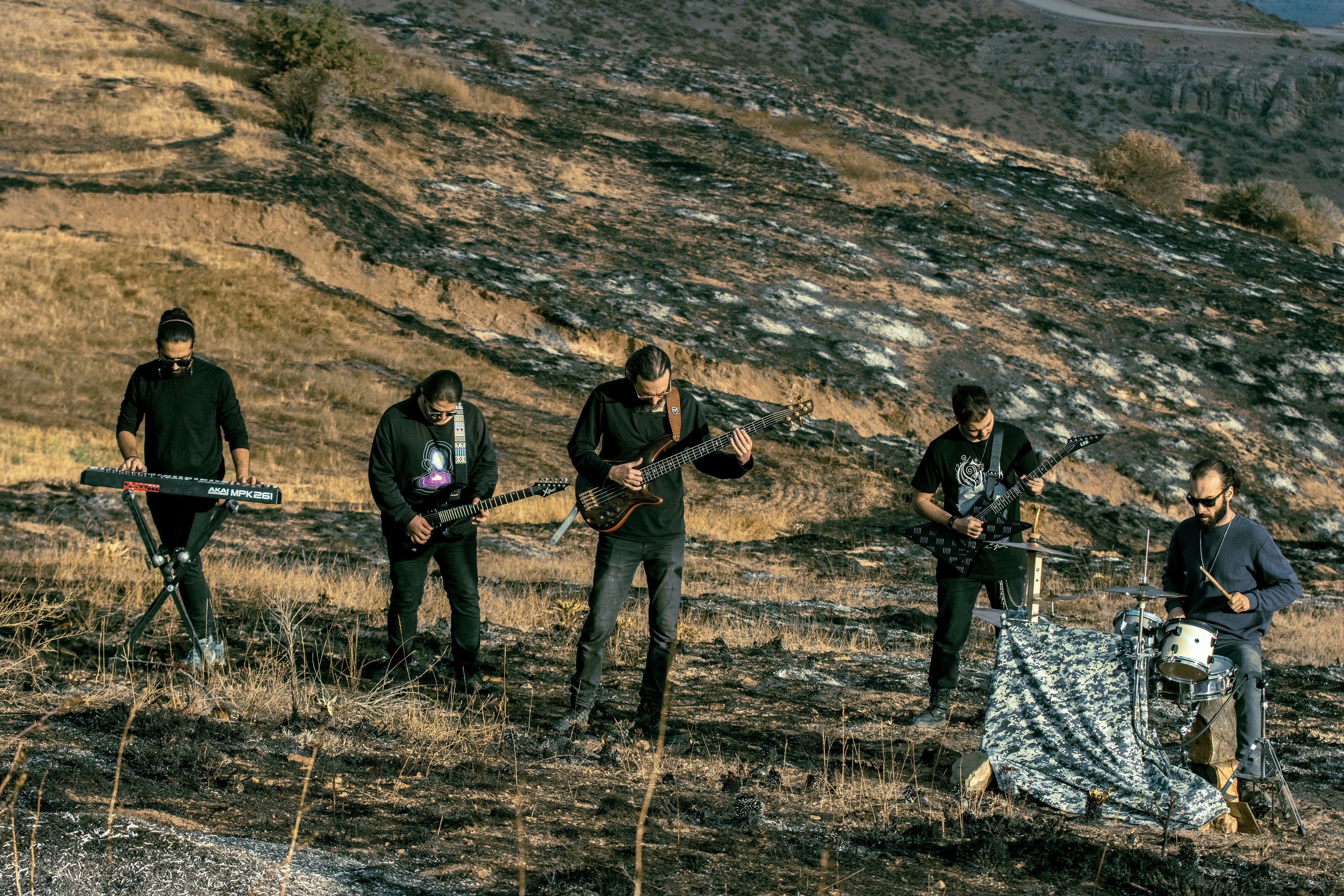 A band playing instruments on a dry, scorched hillside during the golden hour