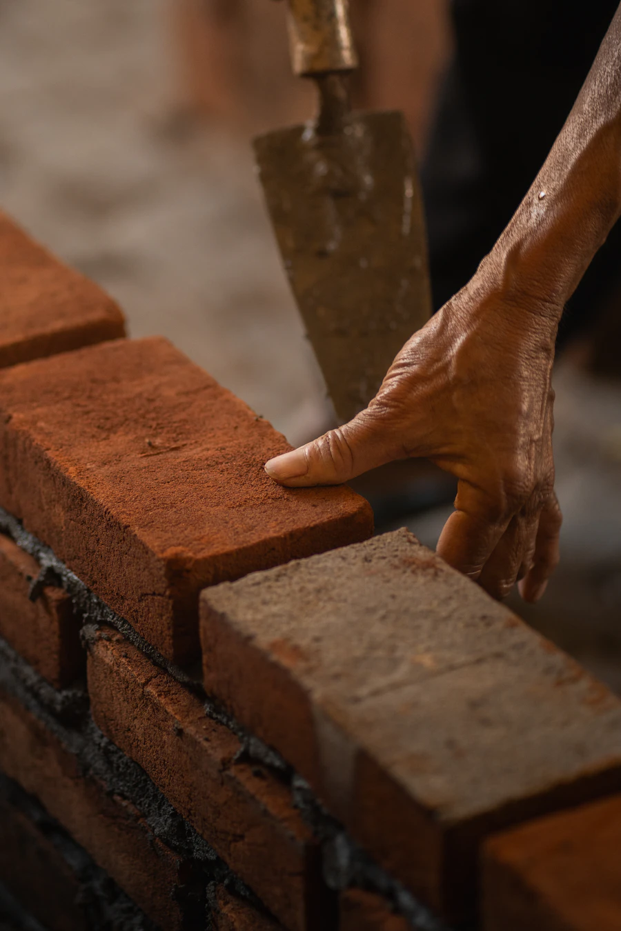 Bricklayer laying a brick with a trowel