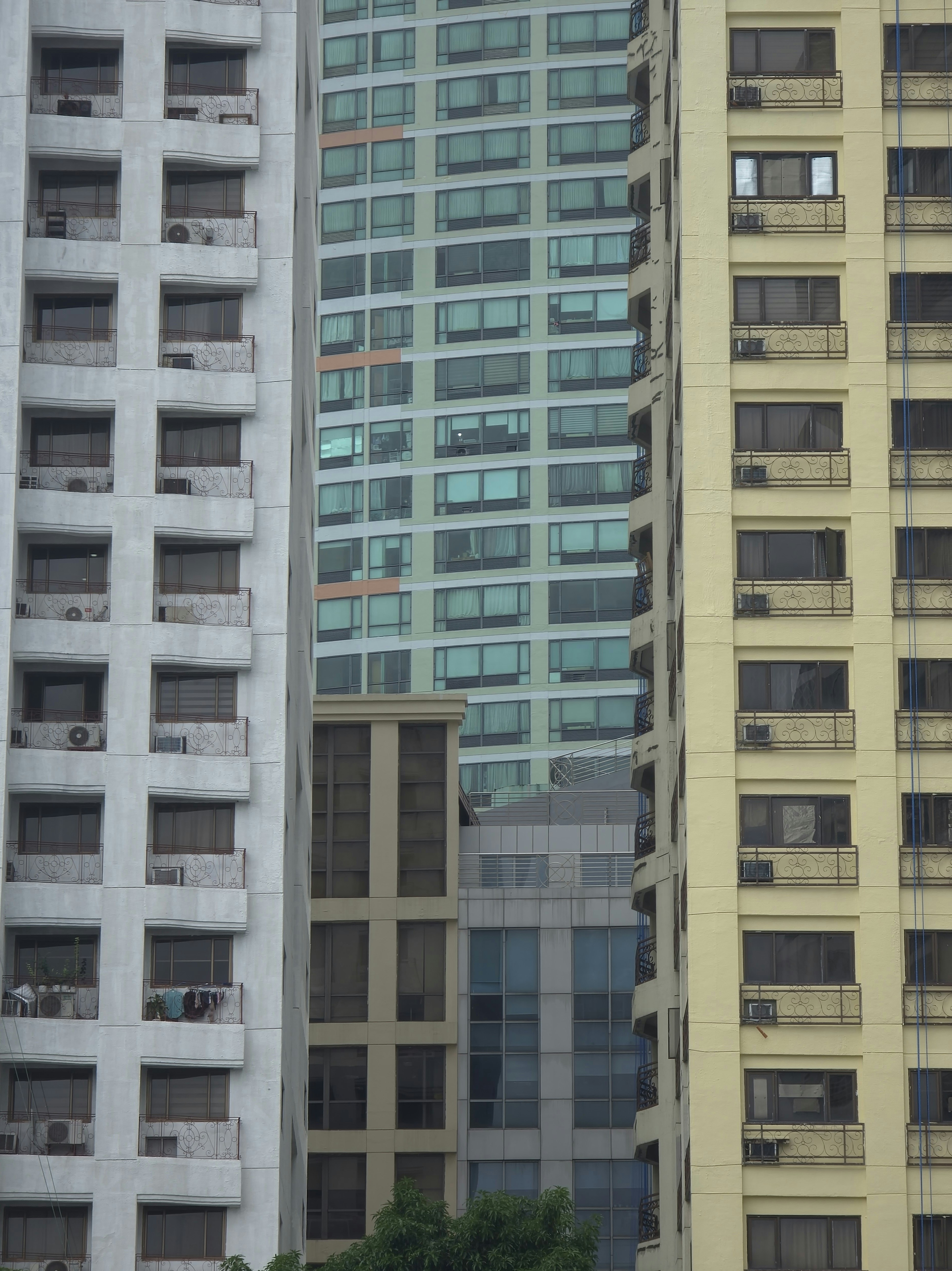 White, yellow, and green apartment buildings with balconies and windows in a city