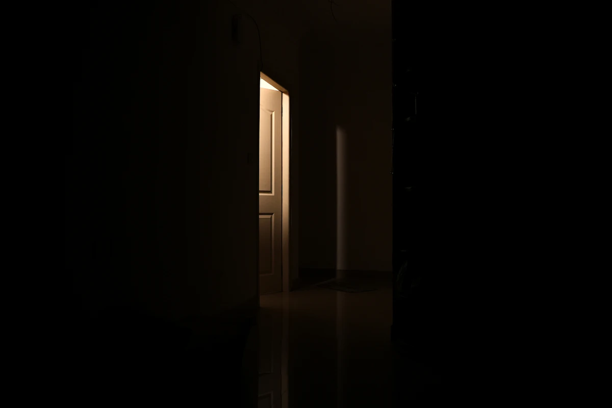 Pintu terbuka sedikit dengan cahaya hangat dalam ruangan gelap