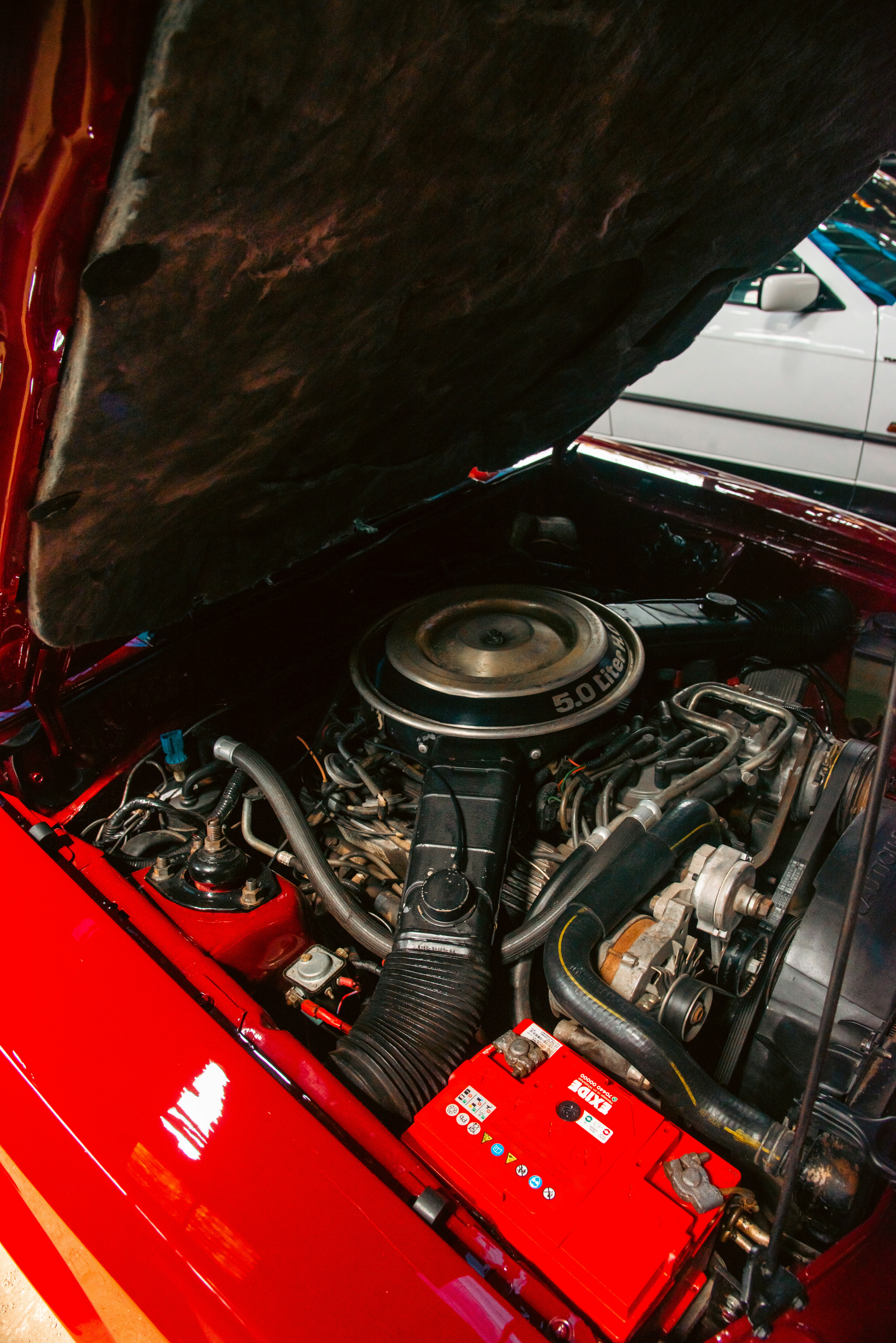 O compartimento do motor de um carro vermelho com o capô aberto