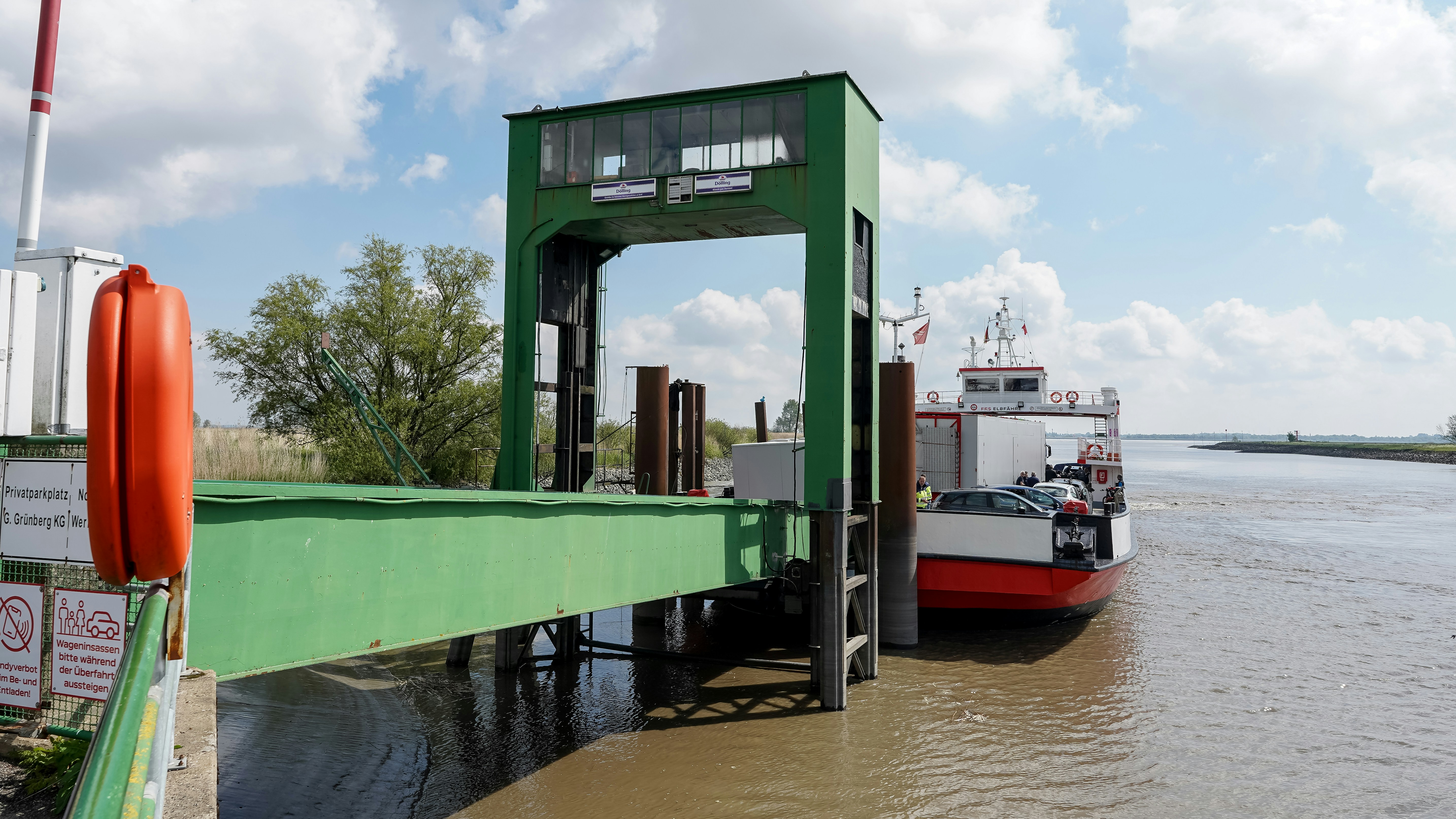 Un ferry atracaba en una rampa metálica verde en un río ancho