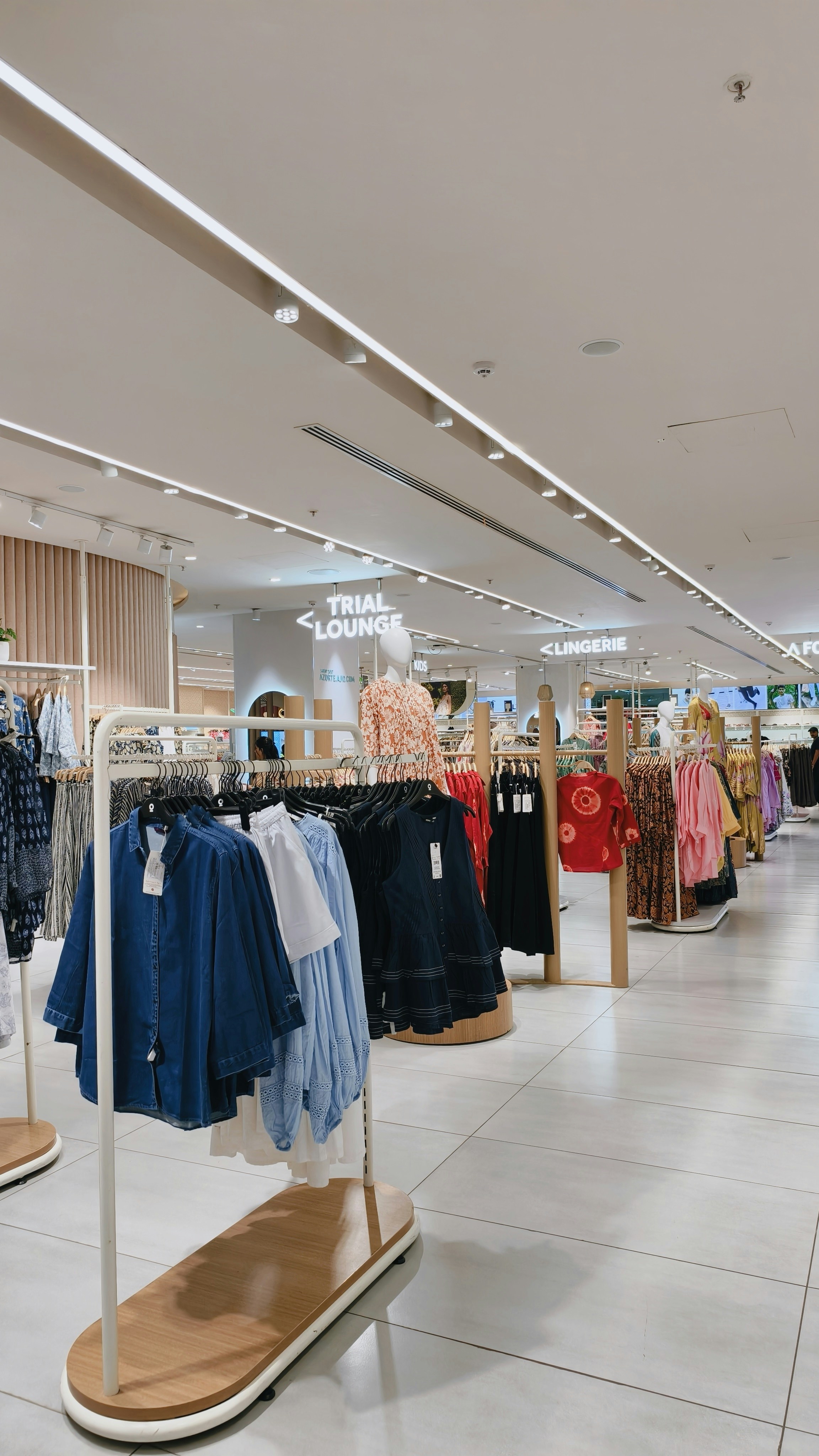 Clothing racks with shirts and dresses in a brightly lit retail store