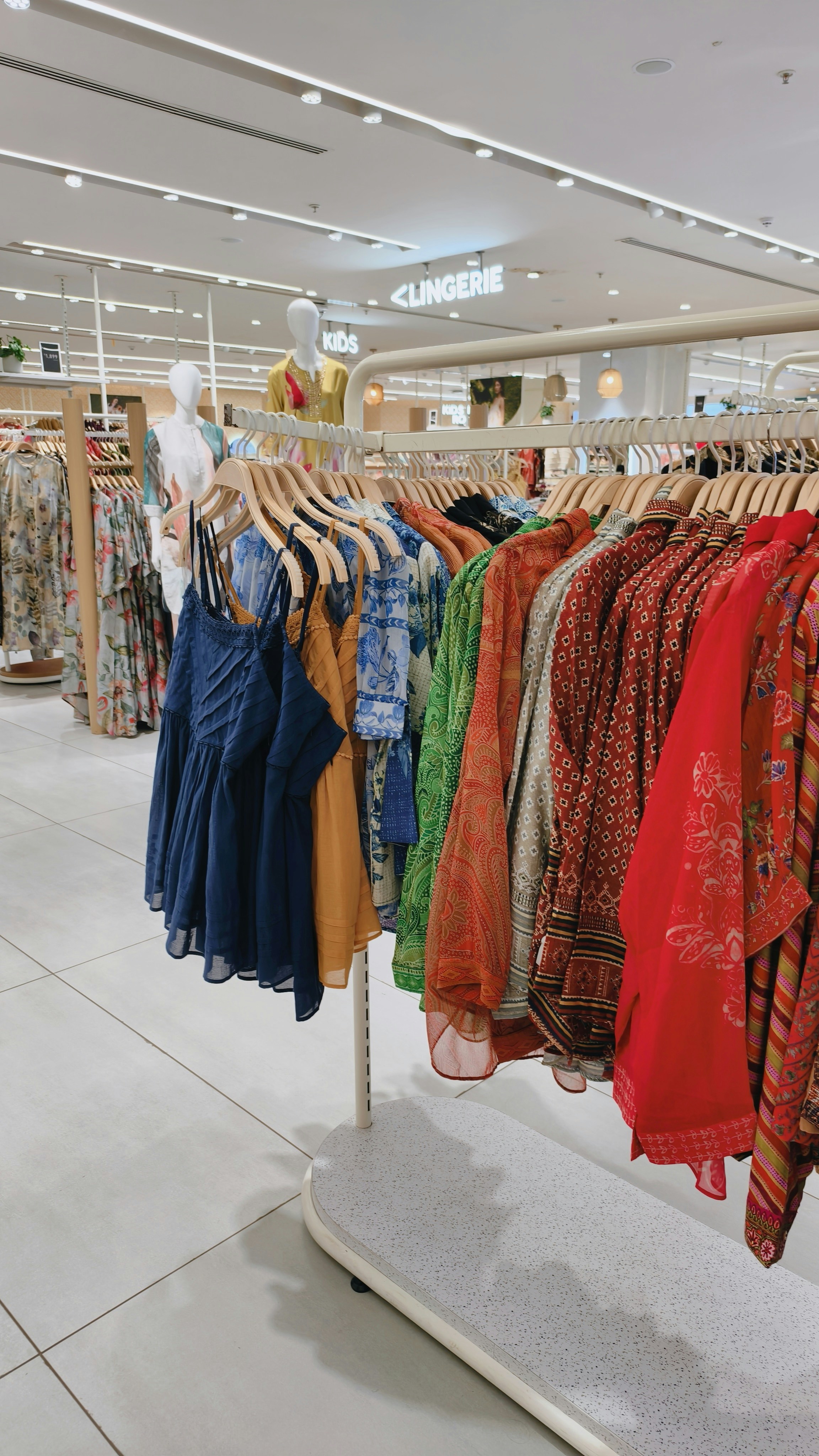 A clothing rack filled with colorful patterned shirts and dresses in a retail store