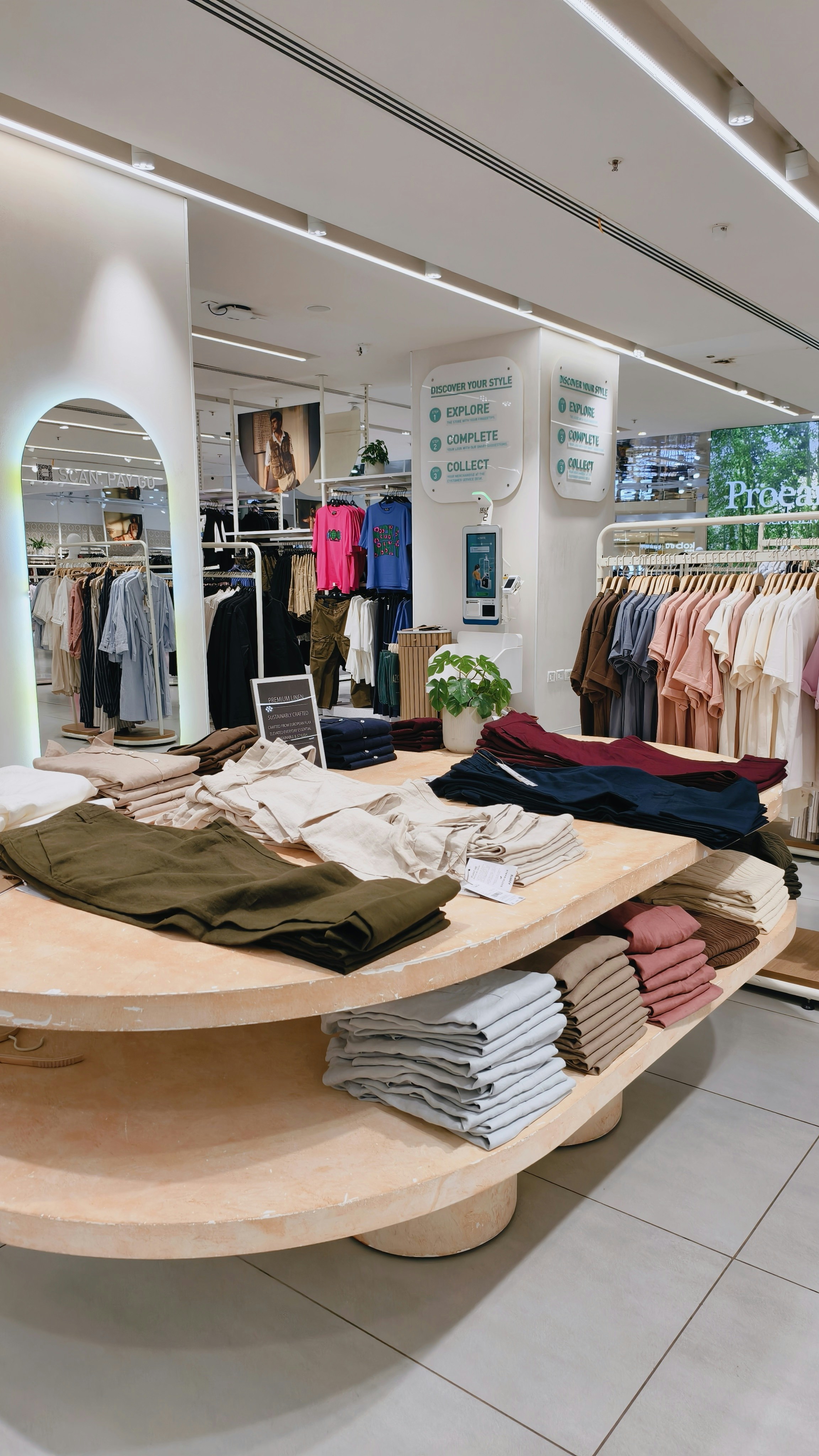 Stacks of folded linen trousers on a large circular table in a clothing store