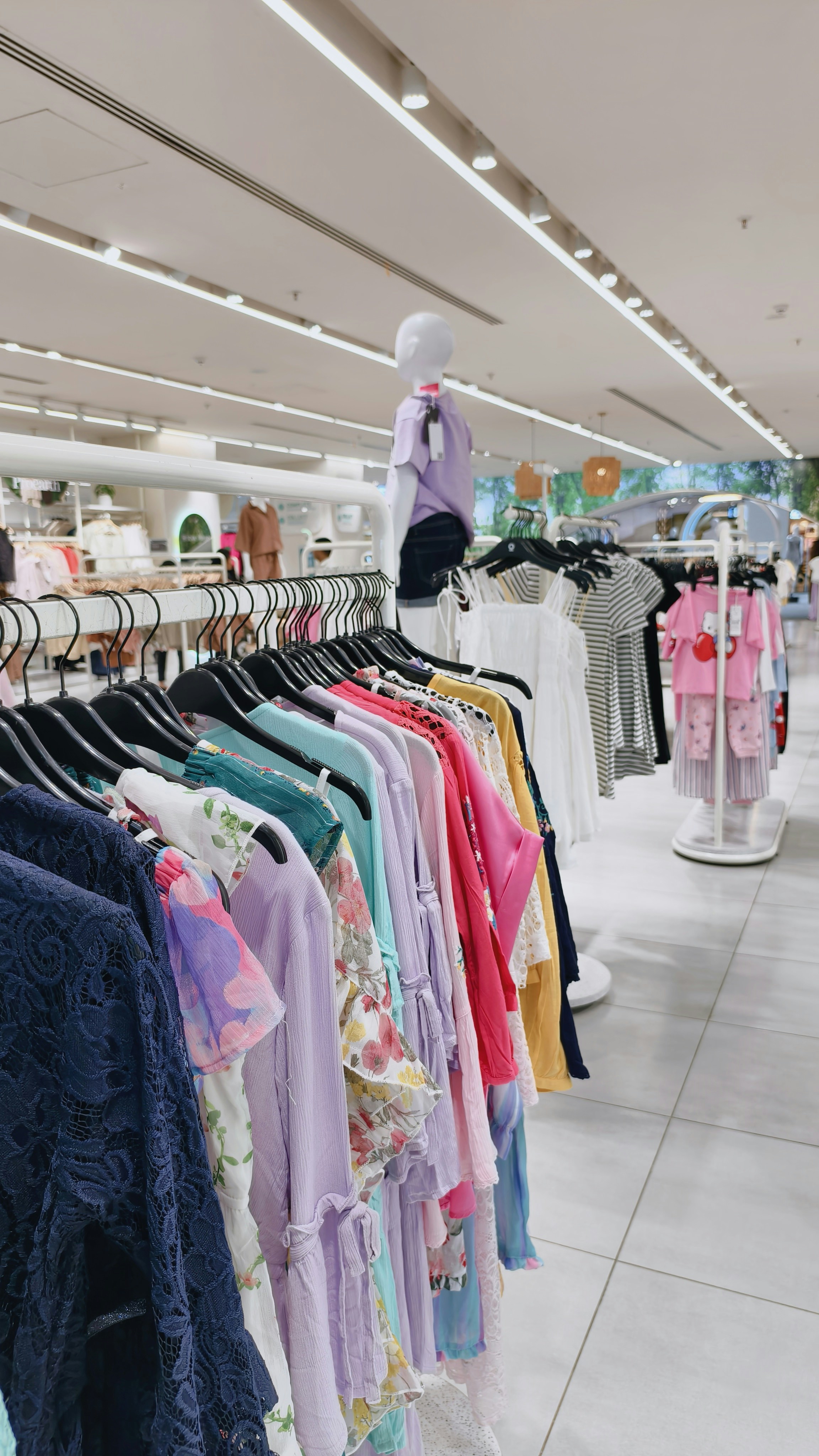 A rack of colorful women's clothing in a bright retail store