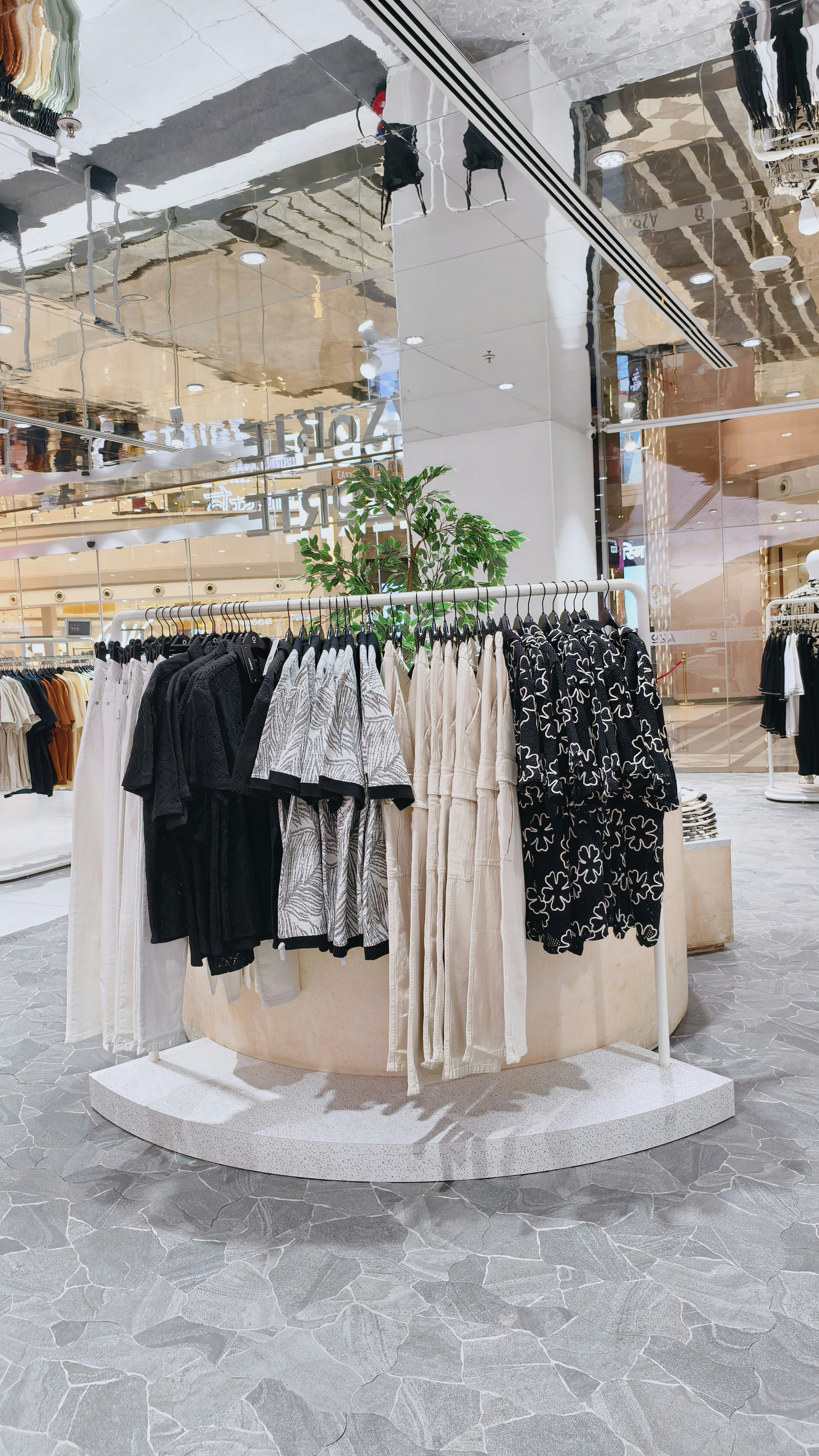 A circular clothing rack with patterned and solid shirts in a retail store