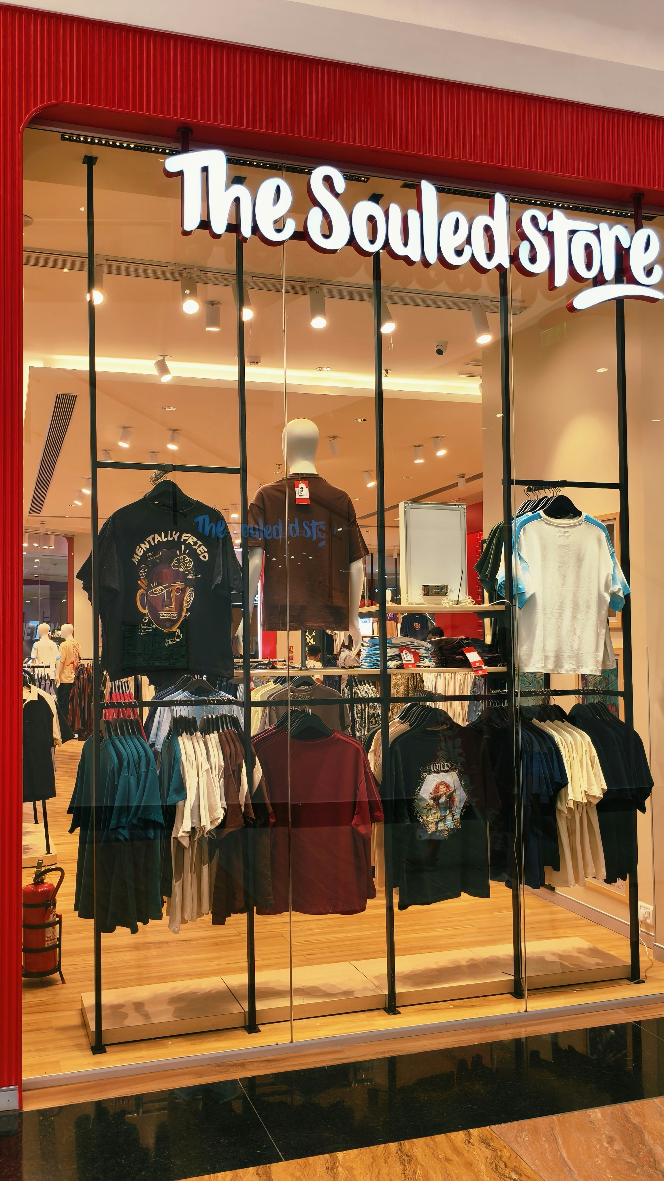 Clothing store window display with t-shirts on hangers and a mannequin
