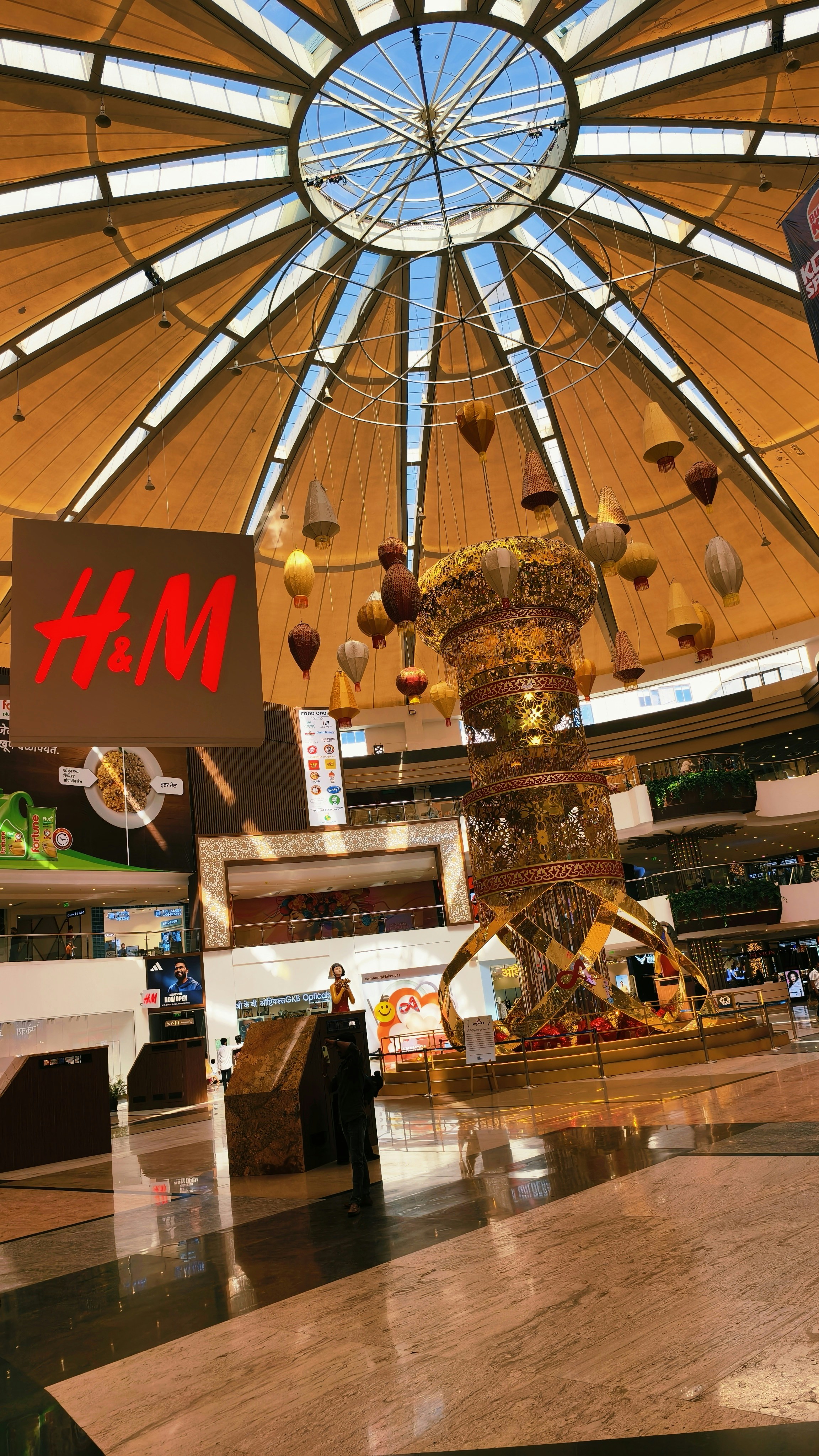 A large golden decorative structure under a domed ceiling in a shopping mall