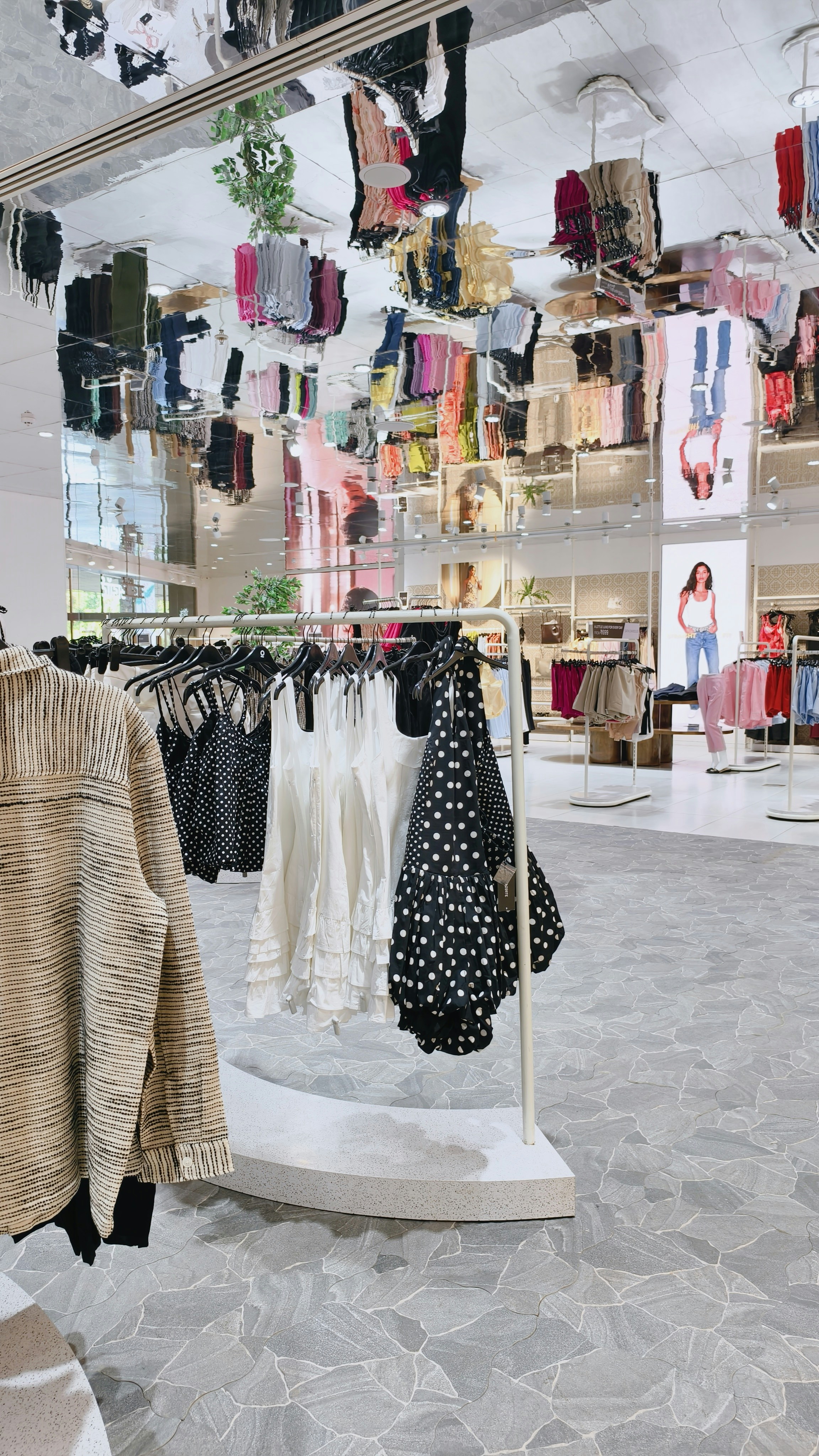 Clothing racks with polka dot and white tops in a bright retail store