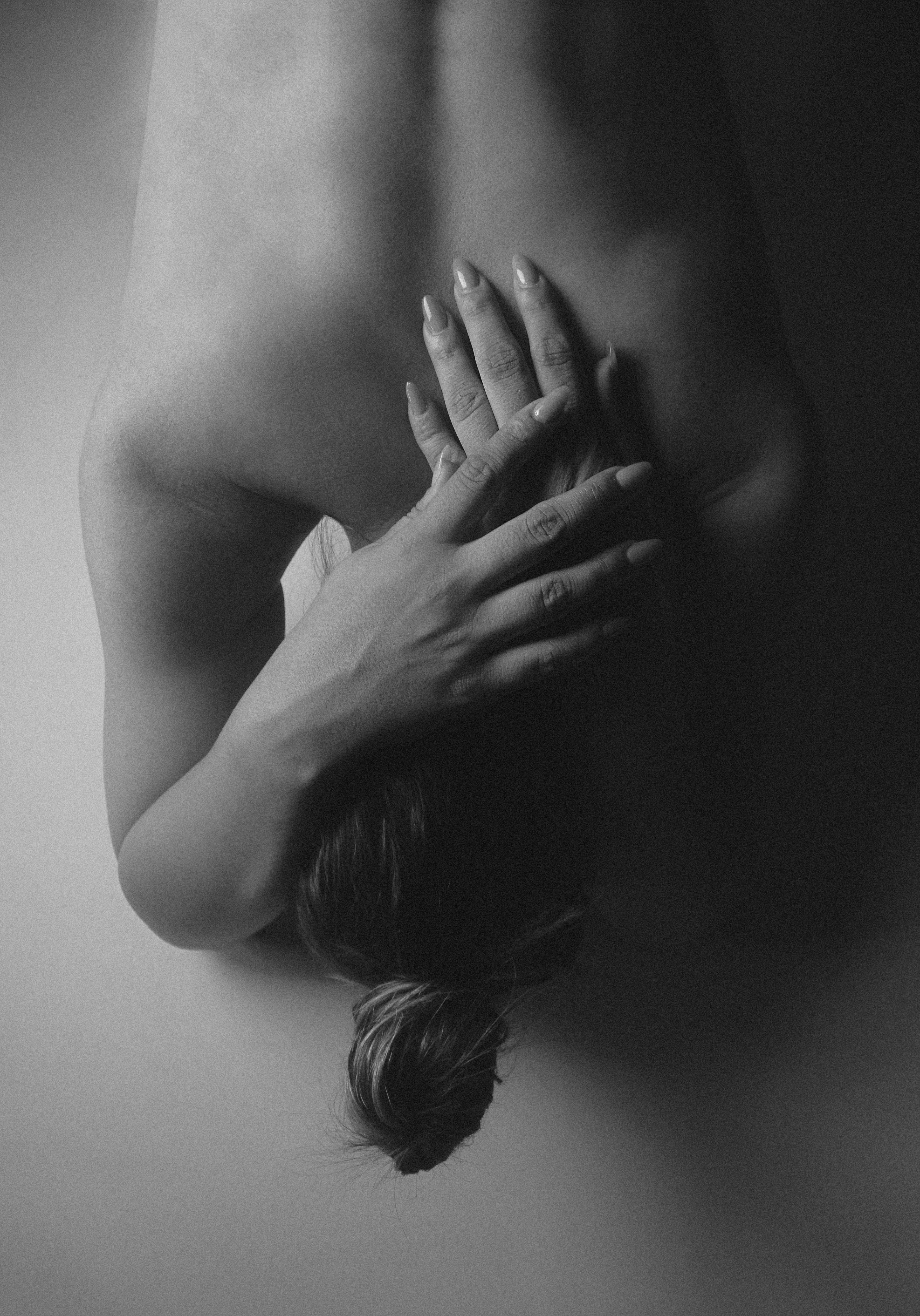 A person with hair in a bun, hands crossed over their upper back