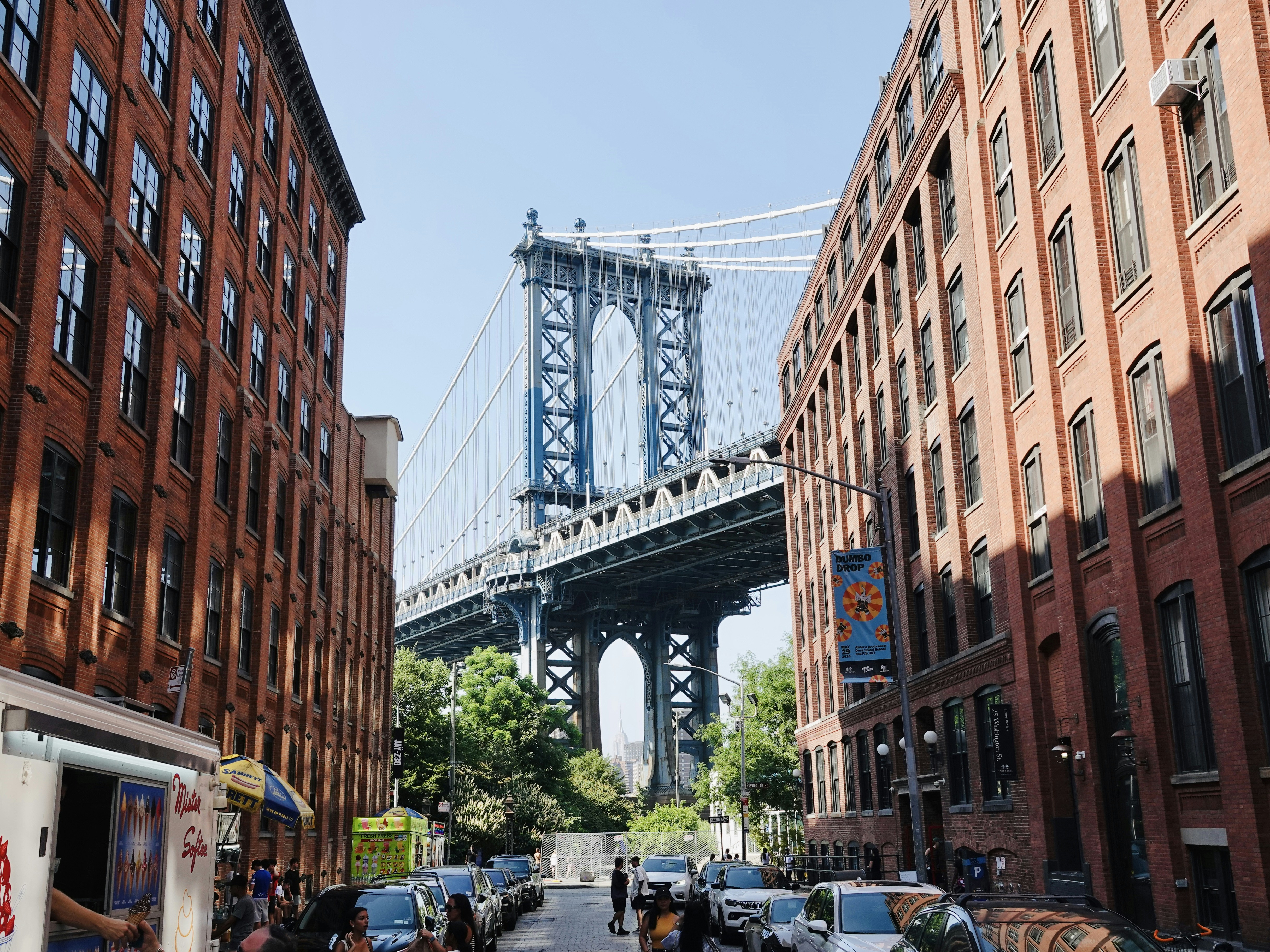The Manhattan Bridge framed by red brick buildings on a street in New York