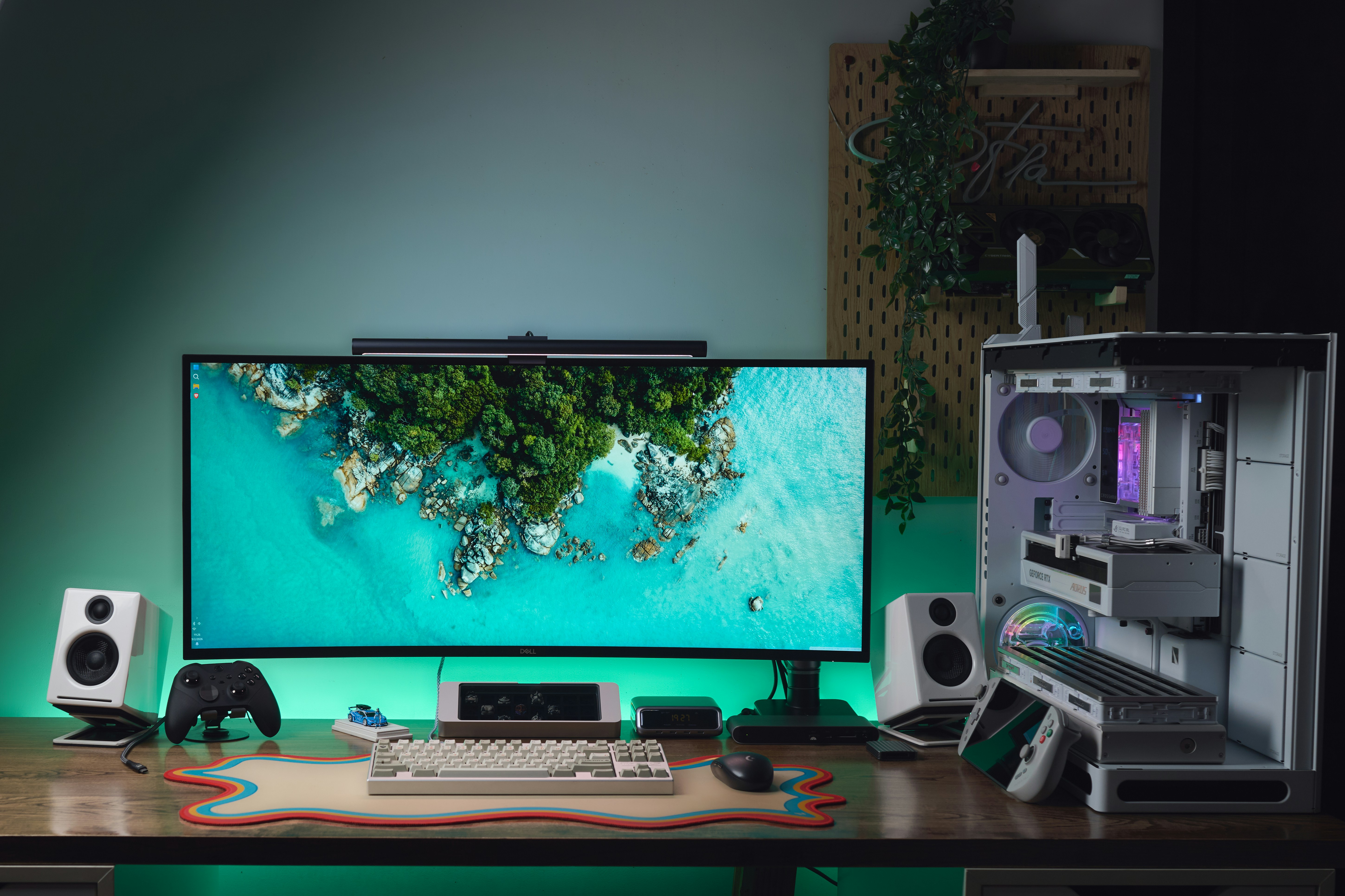 A computer workspace with a curved monitor, white speakers, and a mechanical keyboard
