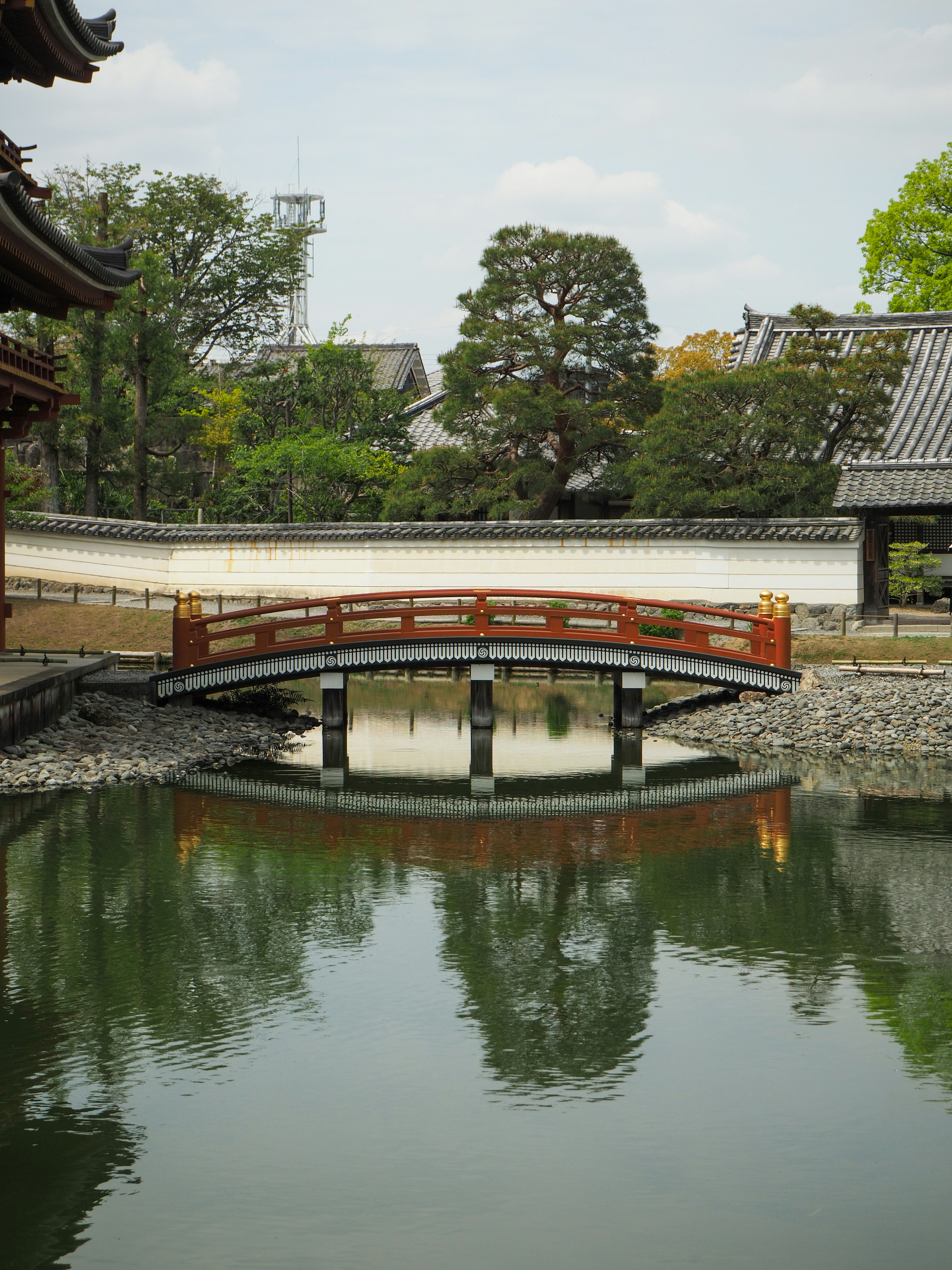日本の寺院庭園にある池にかかる赤いアーチ型の木橋