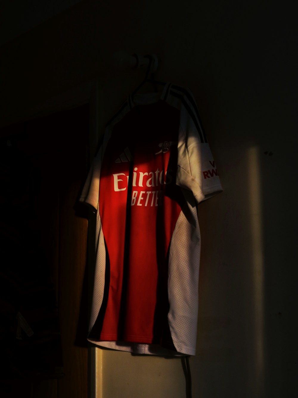 Red and white sports jersey hanging on a wall