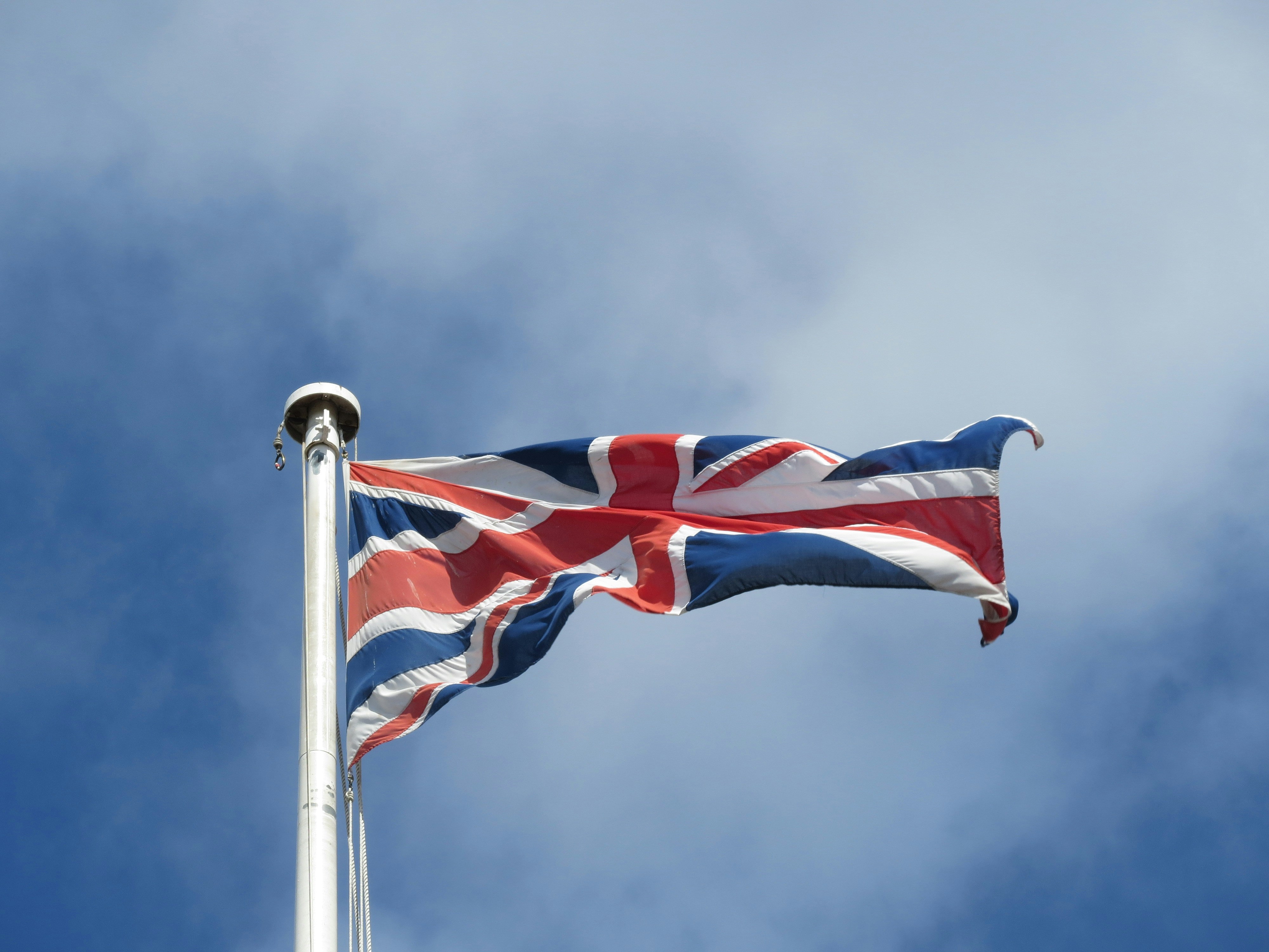 A bandeira da Union Jack tremulando em um mastro contra um céu azul