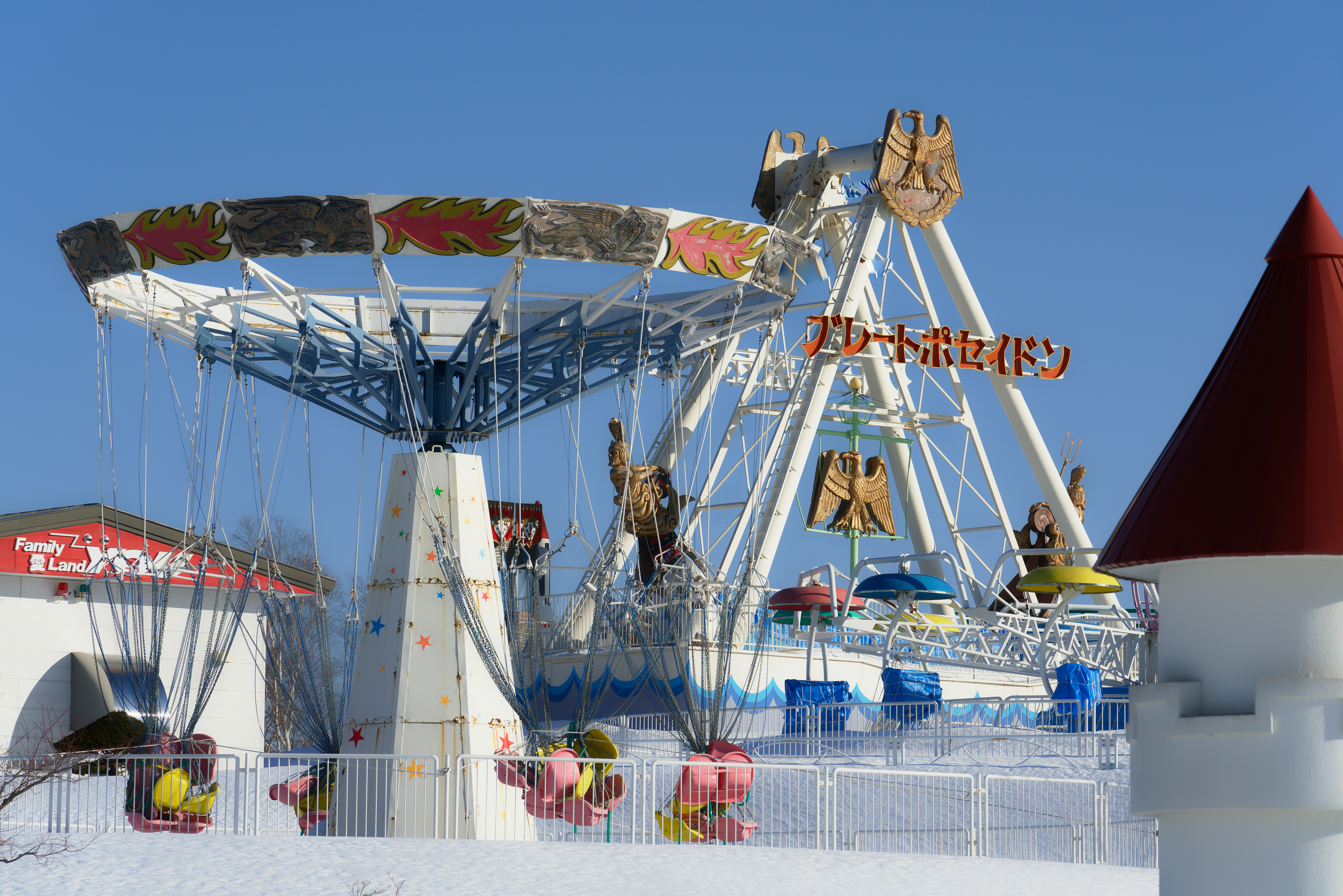Um brinquedo de balanço e um passeio de barco balançante em um parque de diversões nevado