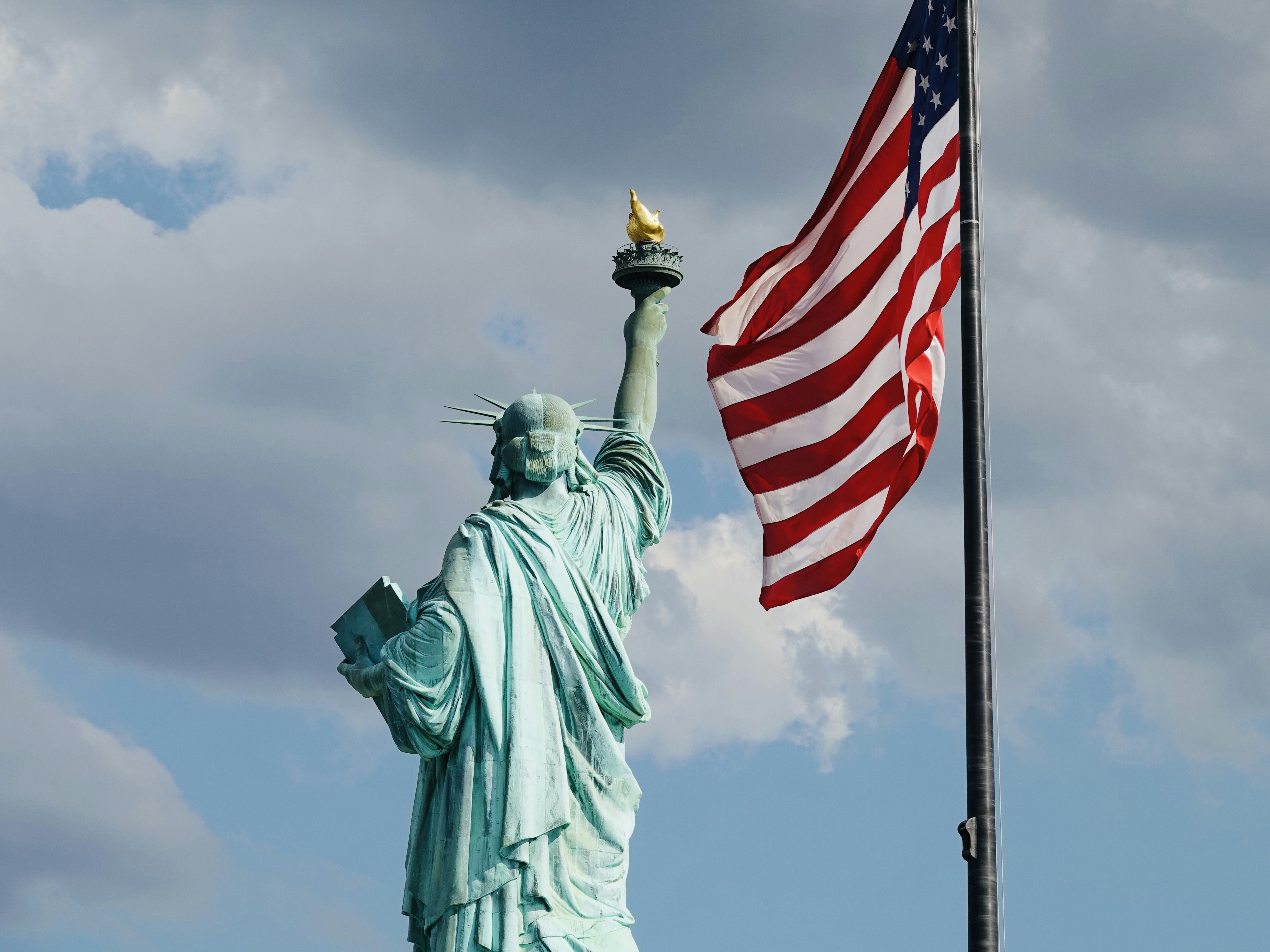 The Statue of Liberty holding a torch beside an American flag in New York