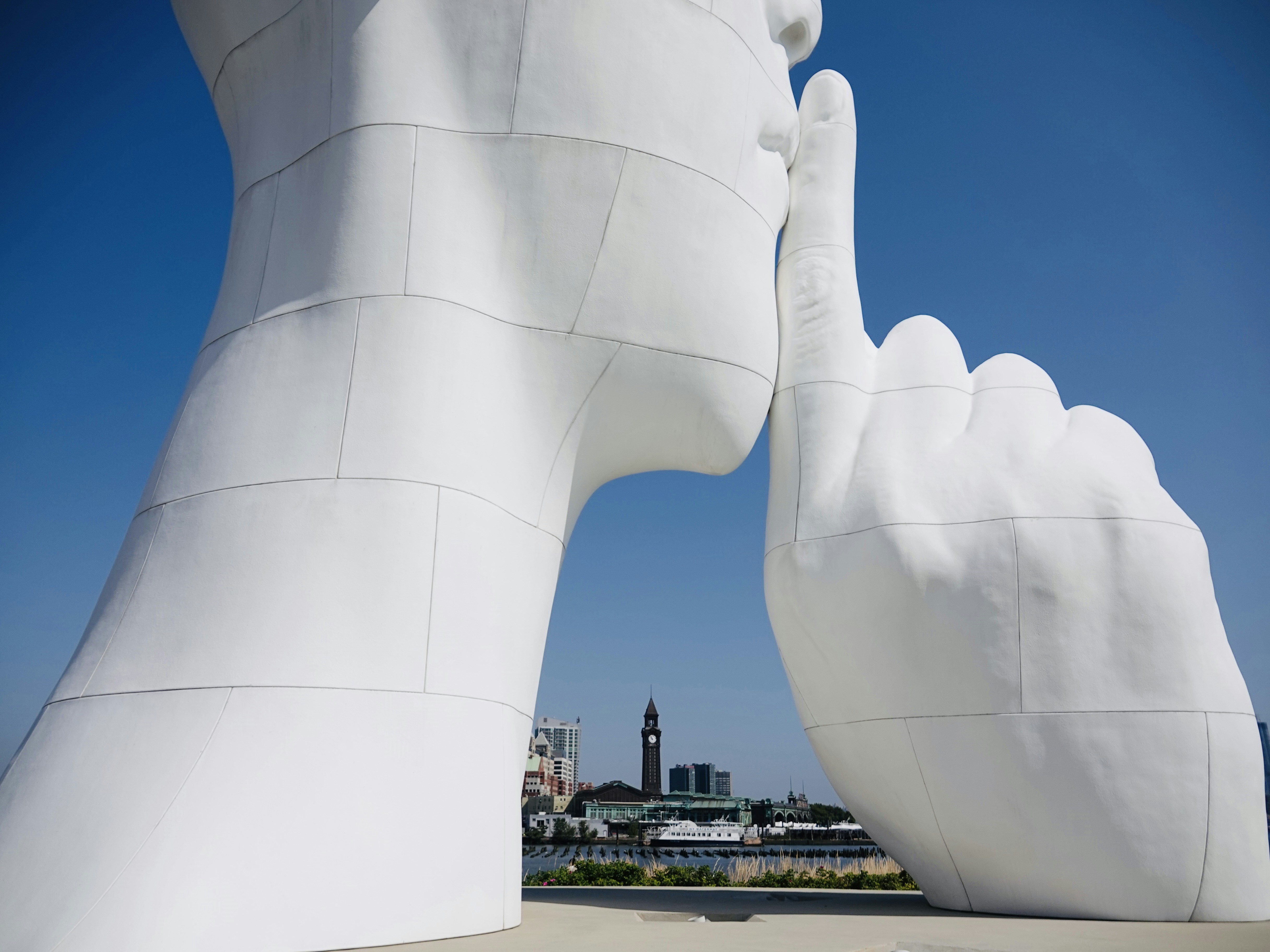 Una grande scultura bianca di un volto con un dito premuto sulle labbra