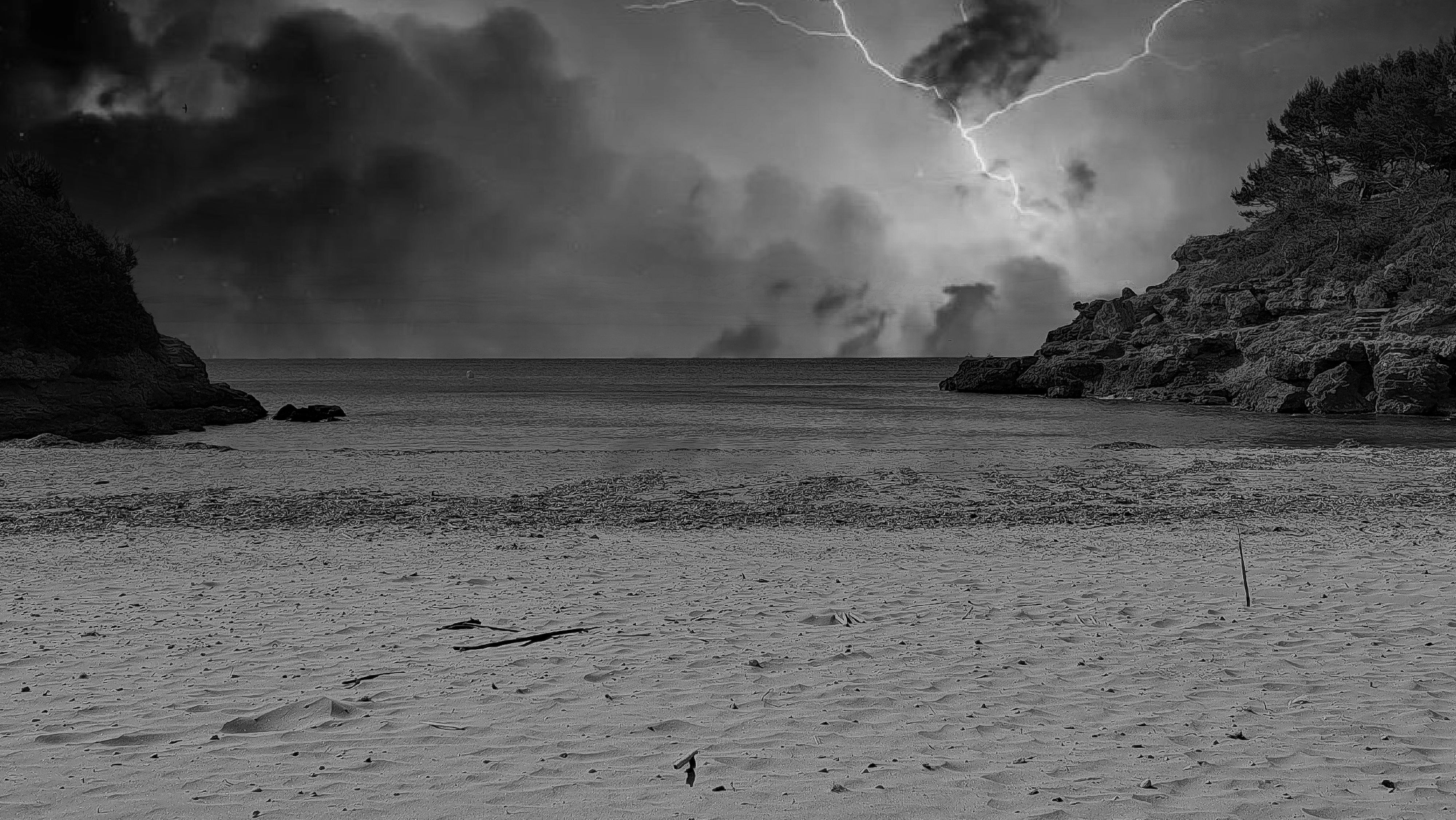 Un éclair frappant une mer sombre entre des falaises rocheuses sur une plage de sable