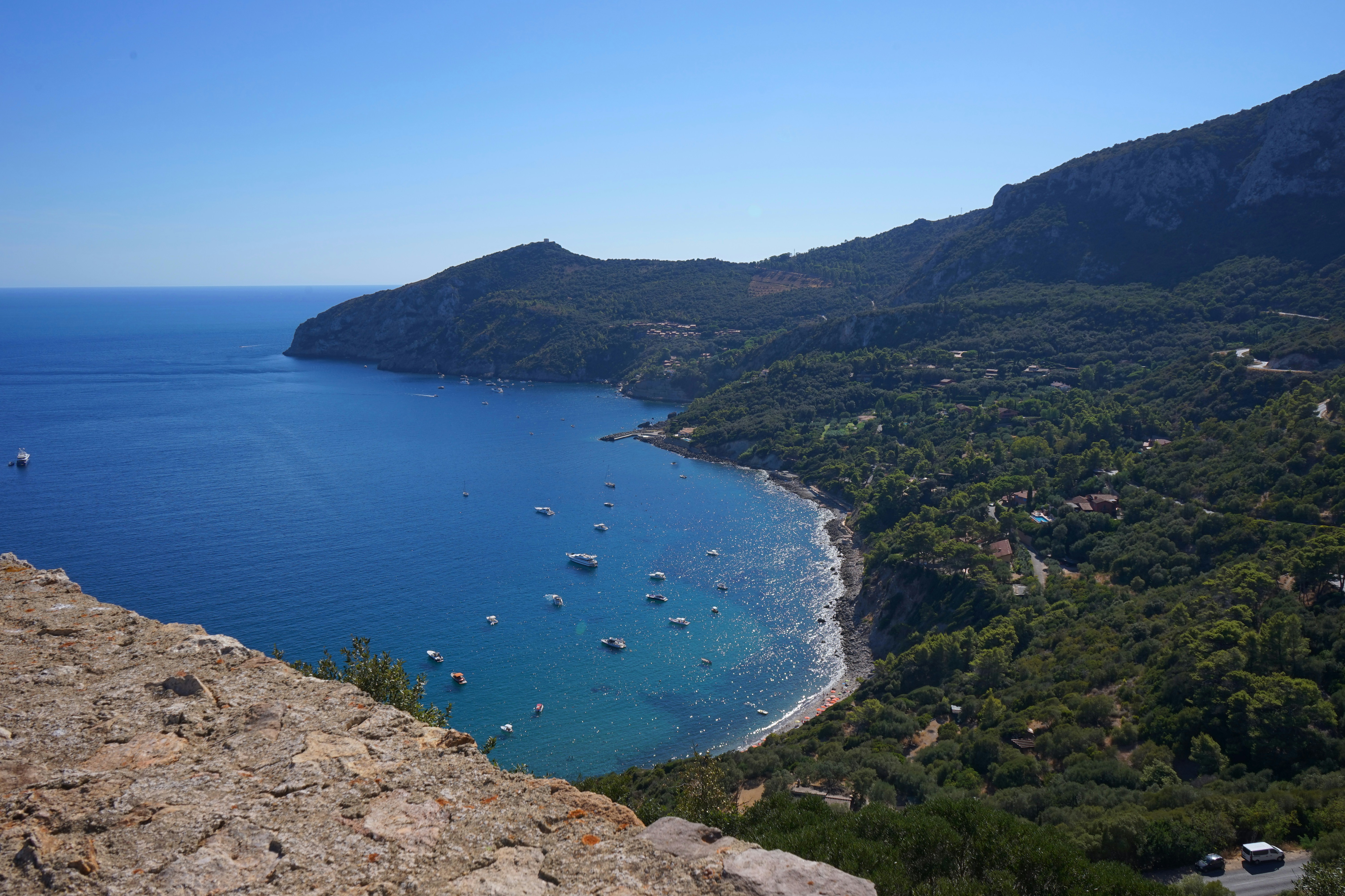 Barche ancorate in una baia blu circondata da colline verdi e scogliere rocciose