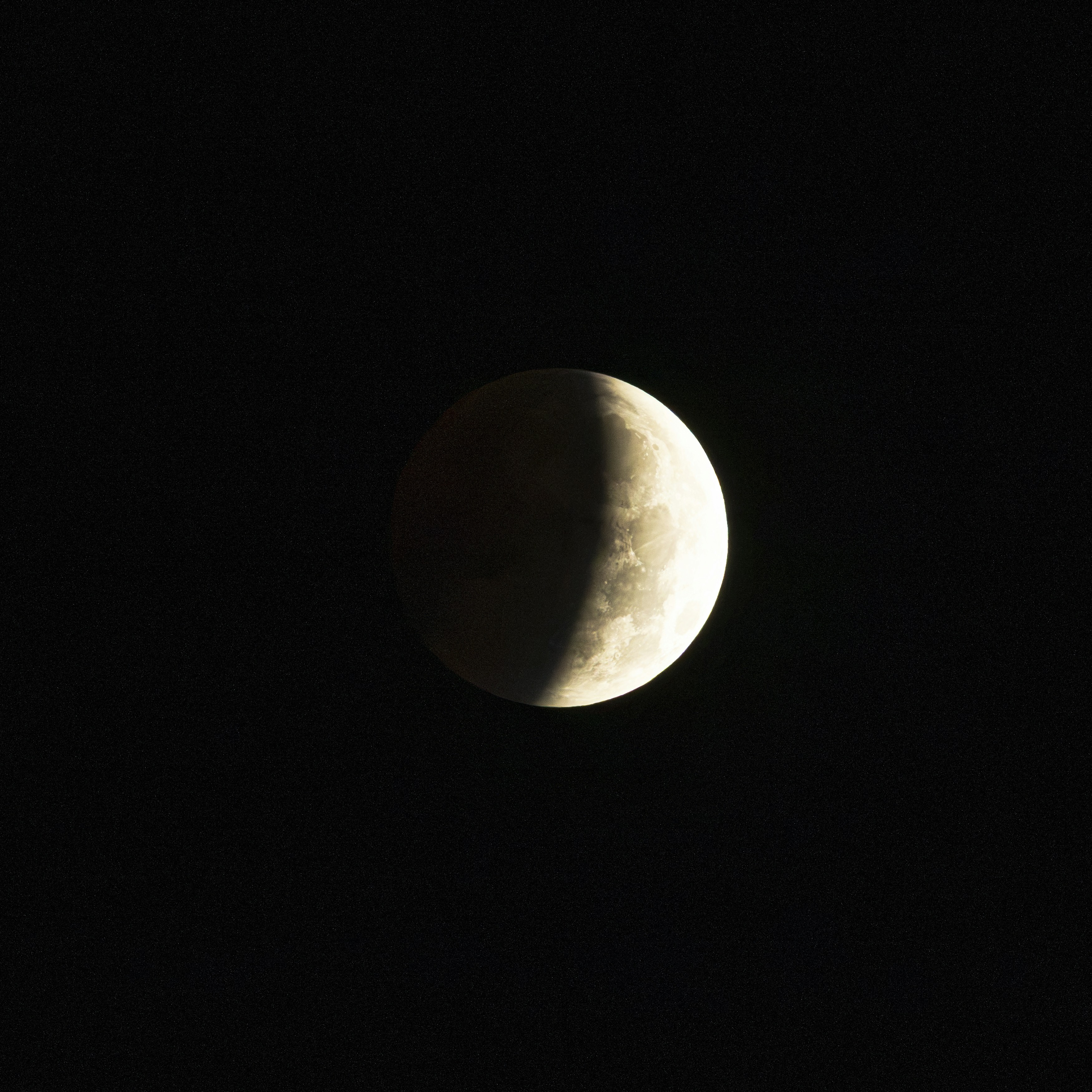 A partially illuminated moon against a dark starry sky