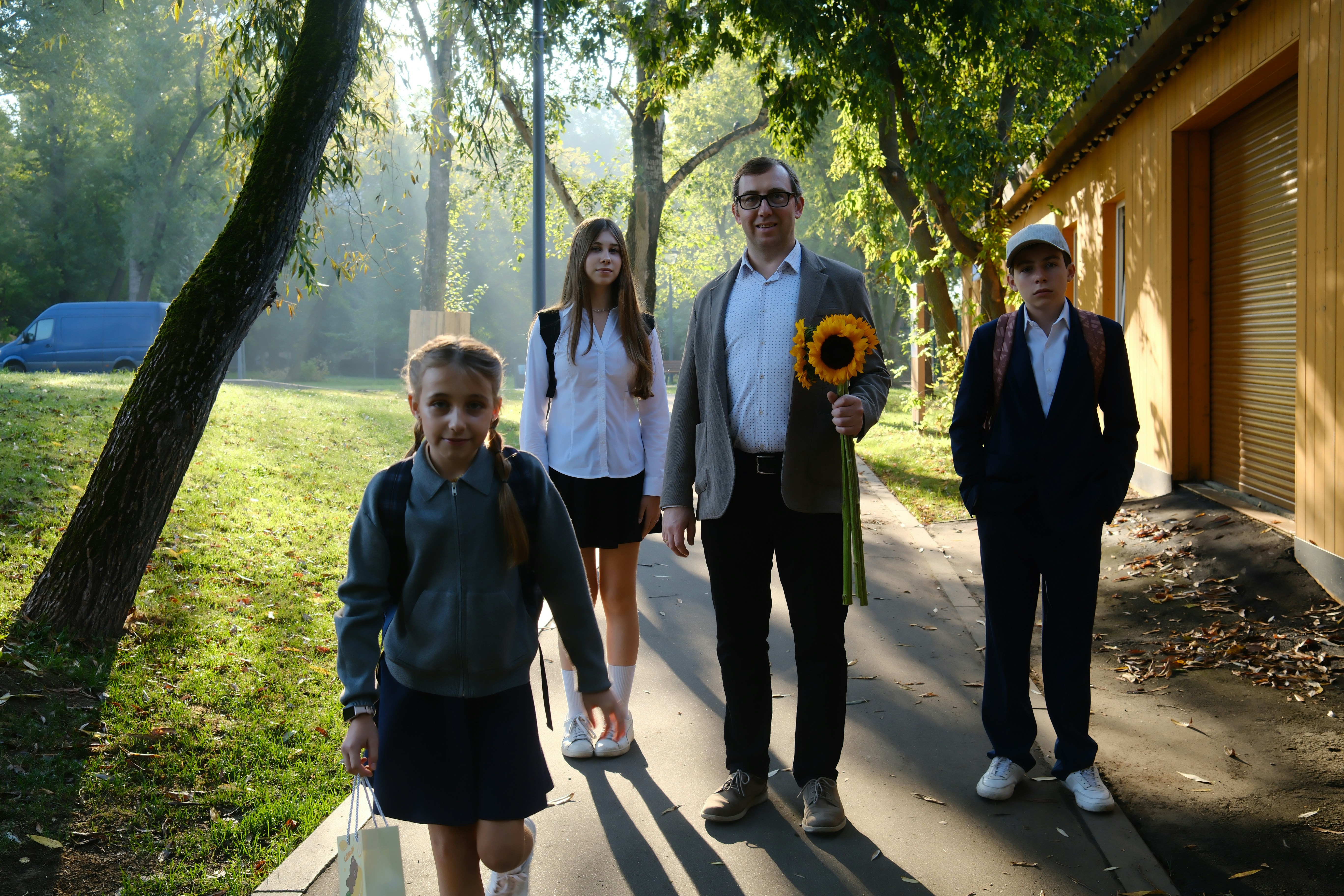 A family on a sunlit path, two adults and two children walking together