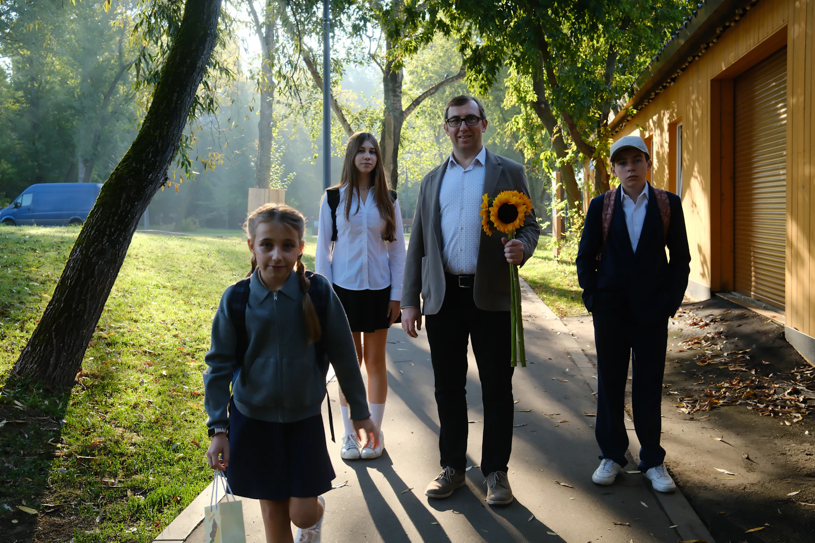 Родина з дітьми йде алеєю до школи