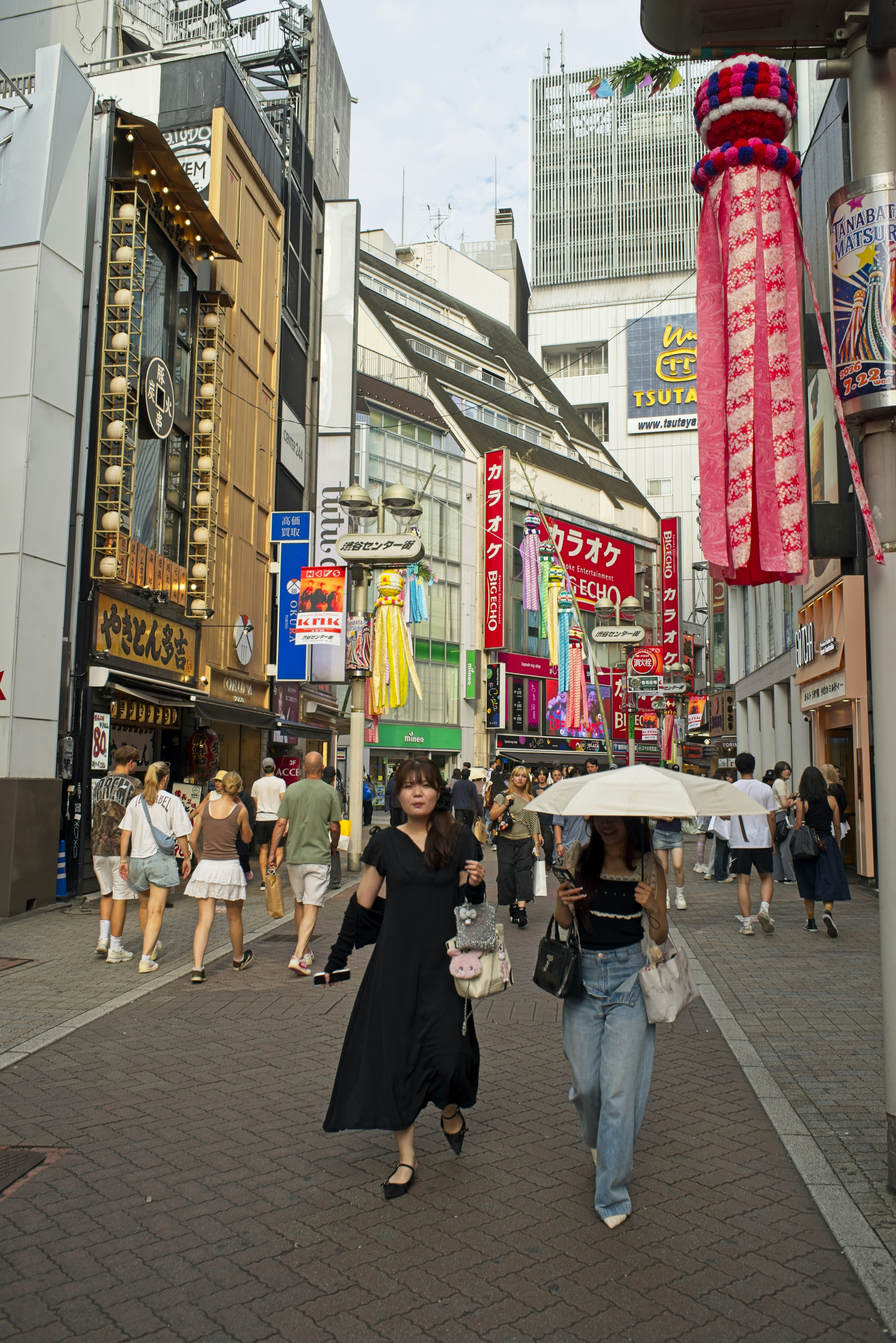People walking on a busy street in Tokyo decorated with colorful paper streamers