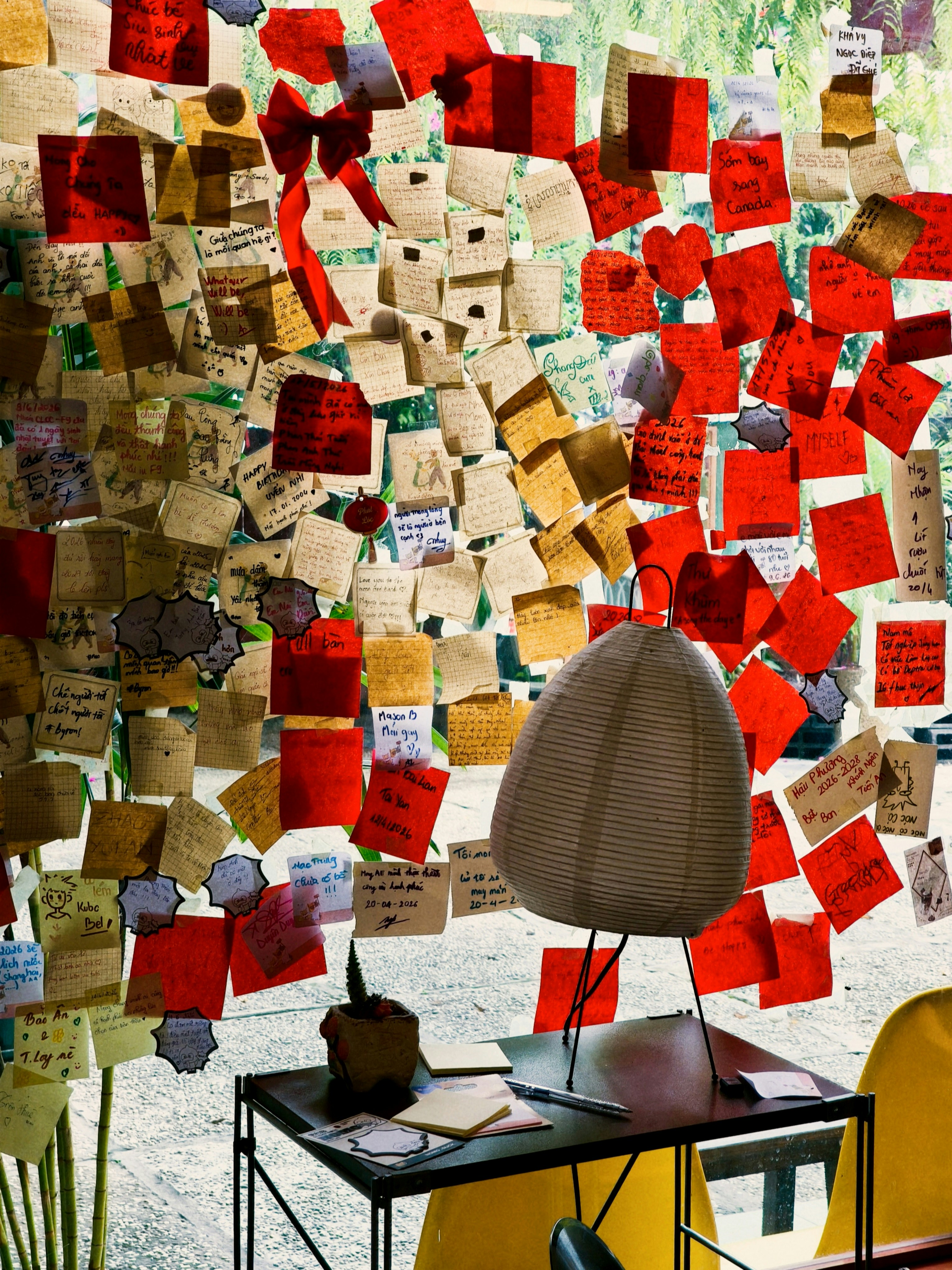 Many red and beige paper notes attached to a glass window with a lamp